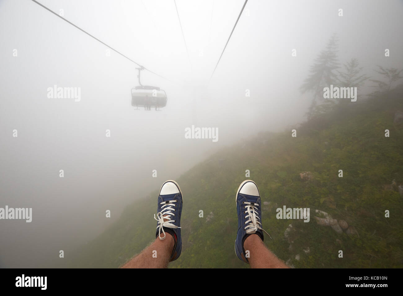 Reisende fahren Mountain Seilbahn erstreckt sich über schöne Frühherbst Berglandschaft im tiefen Nebel. first person Ansicht Stockfoto