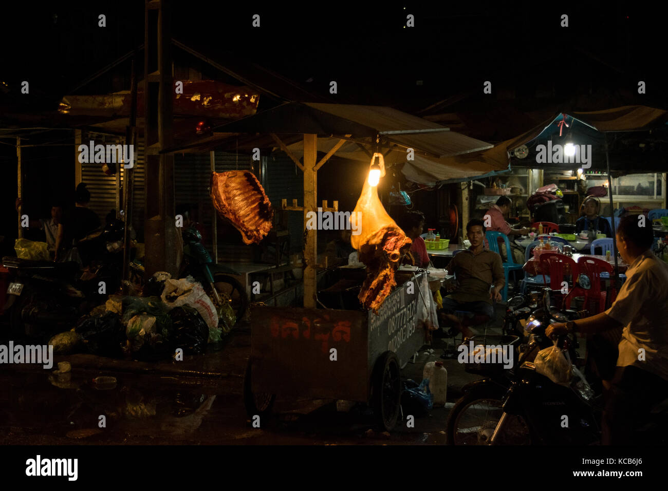 Metzgerei Verkauf von Fleisch in einem mobilen Stand, neben einem lokalen Restaurant in Phnom Penh, Kambodscha. Eine rackof Rippen und ein ganzes Bein ist auf Anzeige aufgehängt. SE-Asien Stockfoto