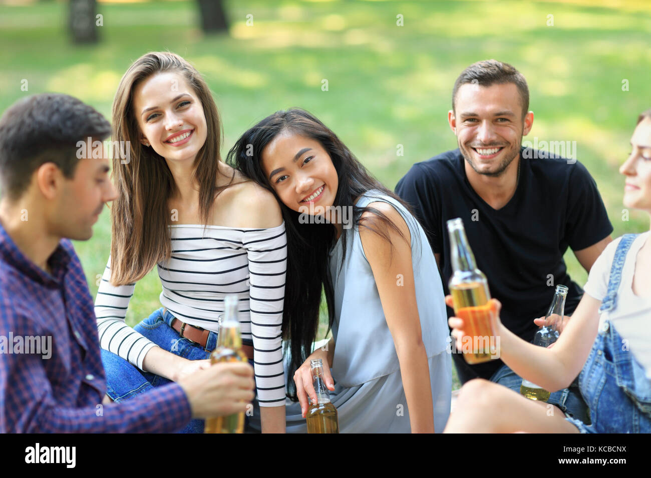 Porträt von zwei Glücklich lächelnde Mädchen und ihre Freunde. Fokus auf junge Frauen. Multirassischen Freundschaft, Freizeit, Outdoor Party Konzept. schöne asiatische Stockfoto