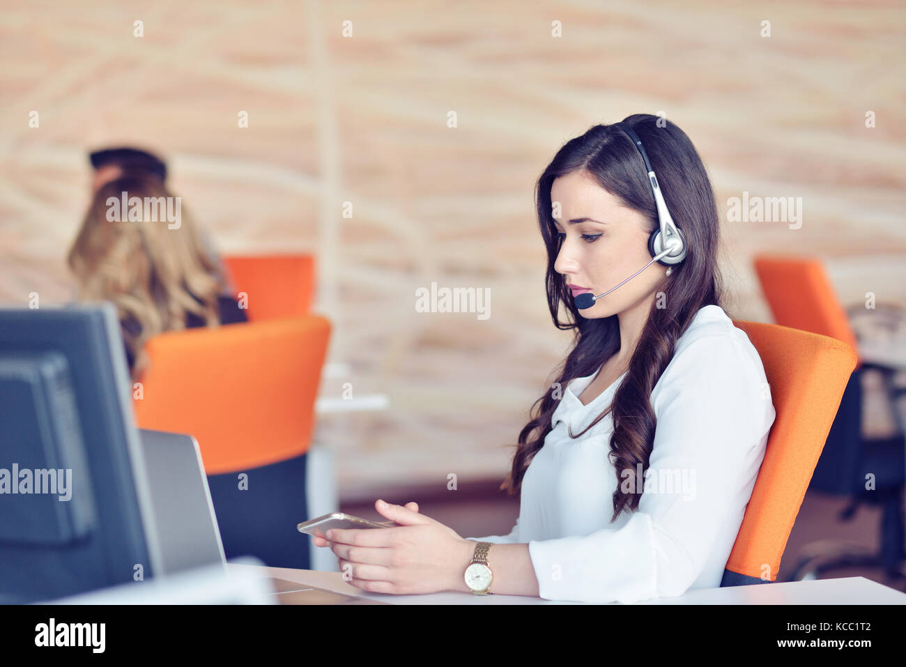 Junge Frau arbeiten im Call Center, von den Kolleginnen und Kollegen umgeben Stockfoto