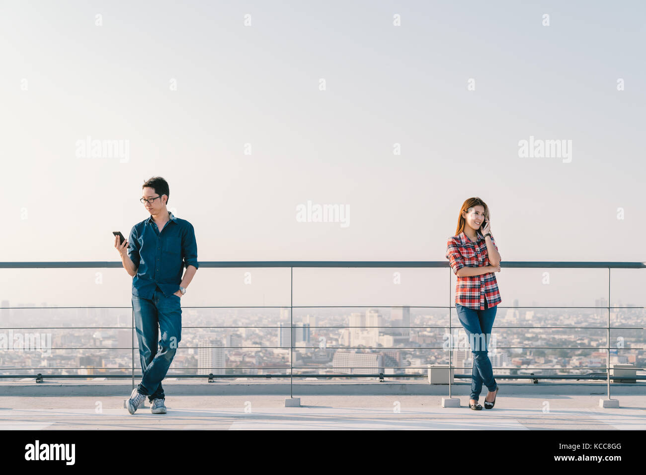 Jungen asiatischen Paar mittels Telefonanruf und zusammen auf Dach smartphone. mobile Handy Gerät oder Informationstechnologie Telekommunikation Stockfoto