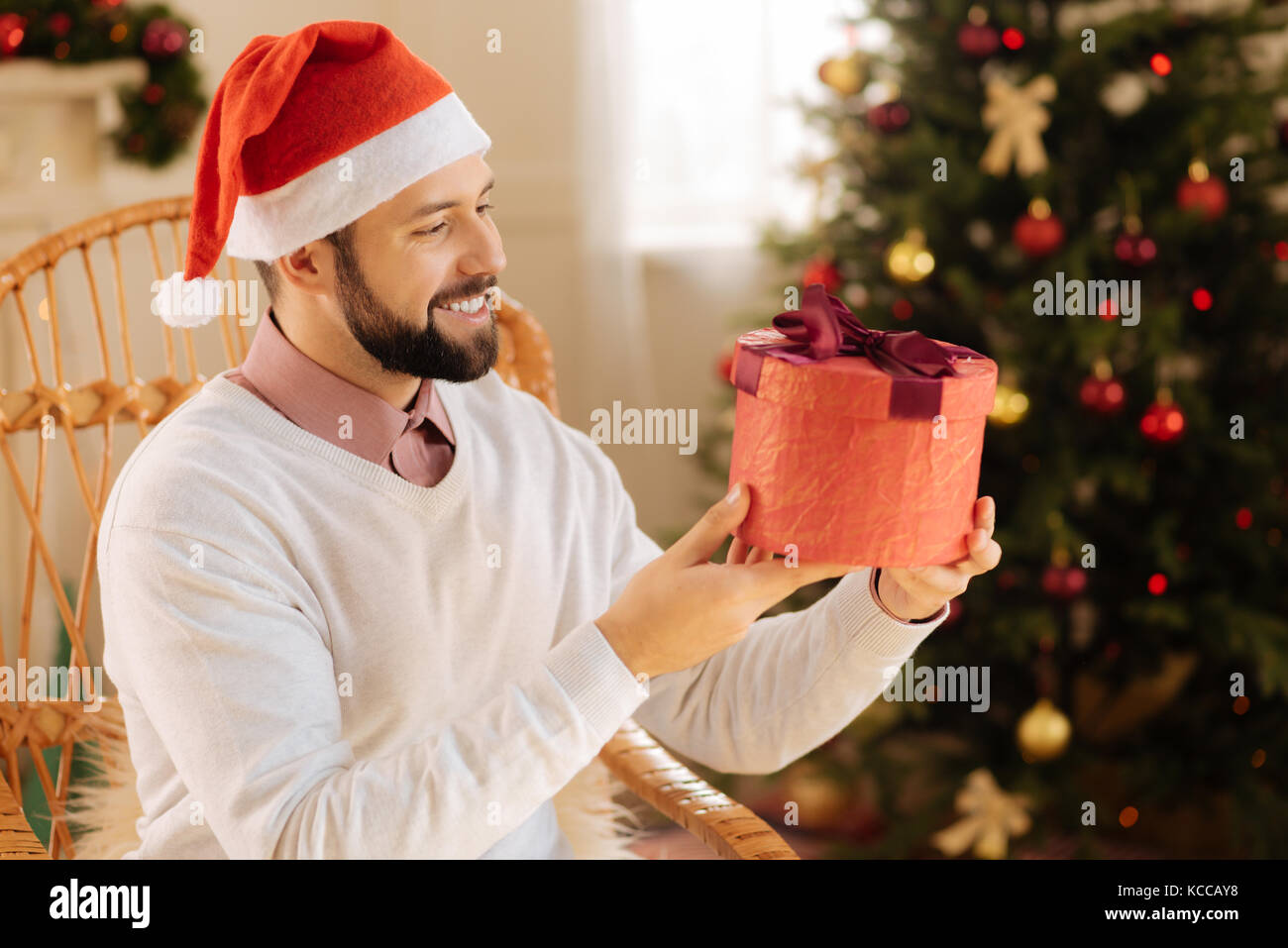 Fröhlicher Mann in Geschenkbox in seinen Händen suchen Stockfoto