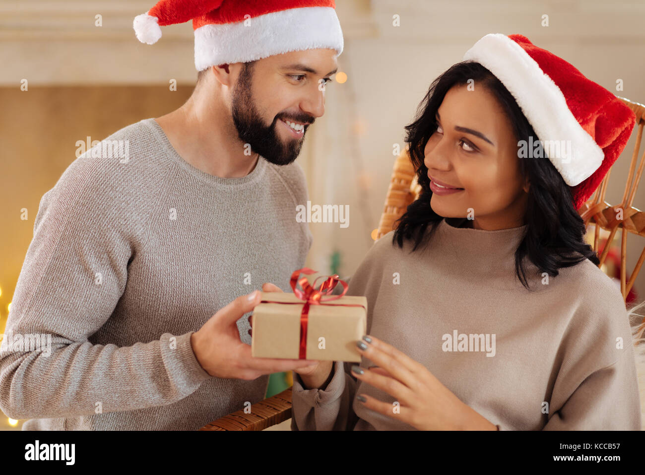 Lächelnd Mann in Santa hat das Weihnachtsgeschenk zu Frau Stockfoto