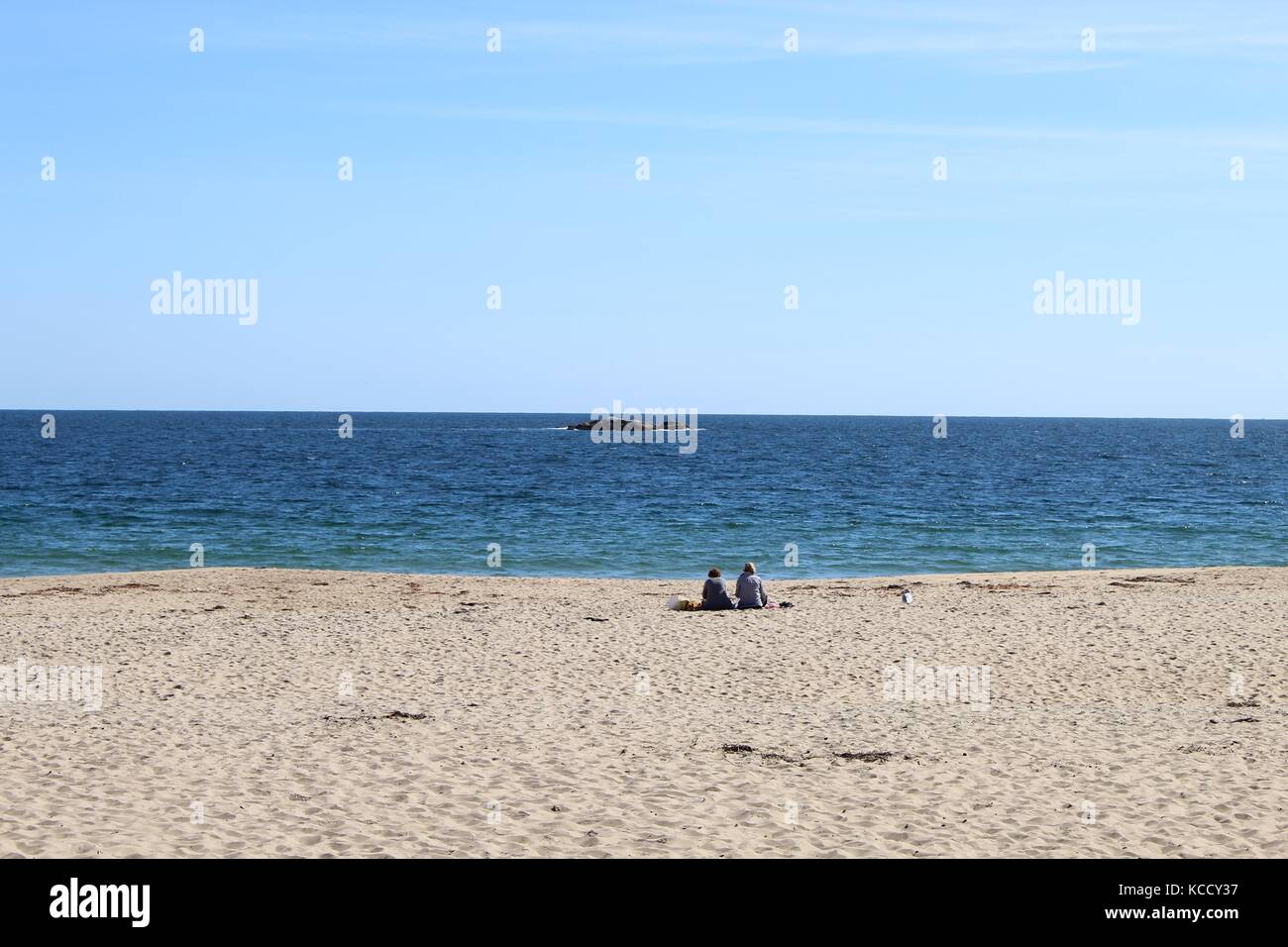 Ein paar genießt den Strand am Atlantischen Ozean in New England beim Sitzen auf dem Sand und Reden und geniessen Sie den Nachmittag am Wasser Stockfoto
