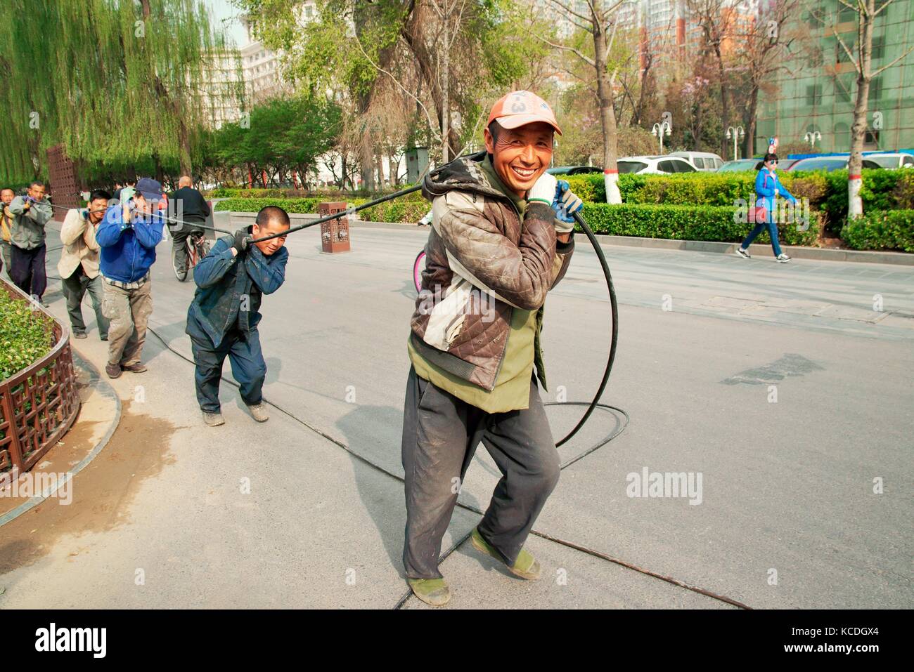 Glückliche chinesische Bauarbeiter Arbeiter Arbeiter Arbeiter, die Kabel auf der Yingze Street im Stadtzentrum von Taiyuan, Provinz Shanxi, China, transportieren Stockfoto
