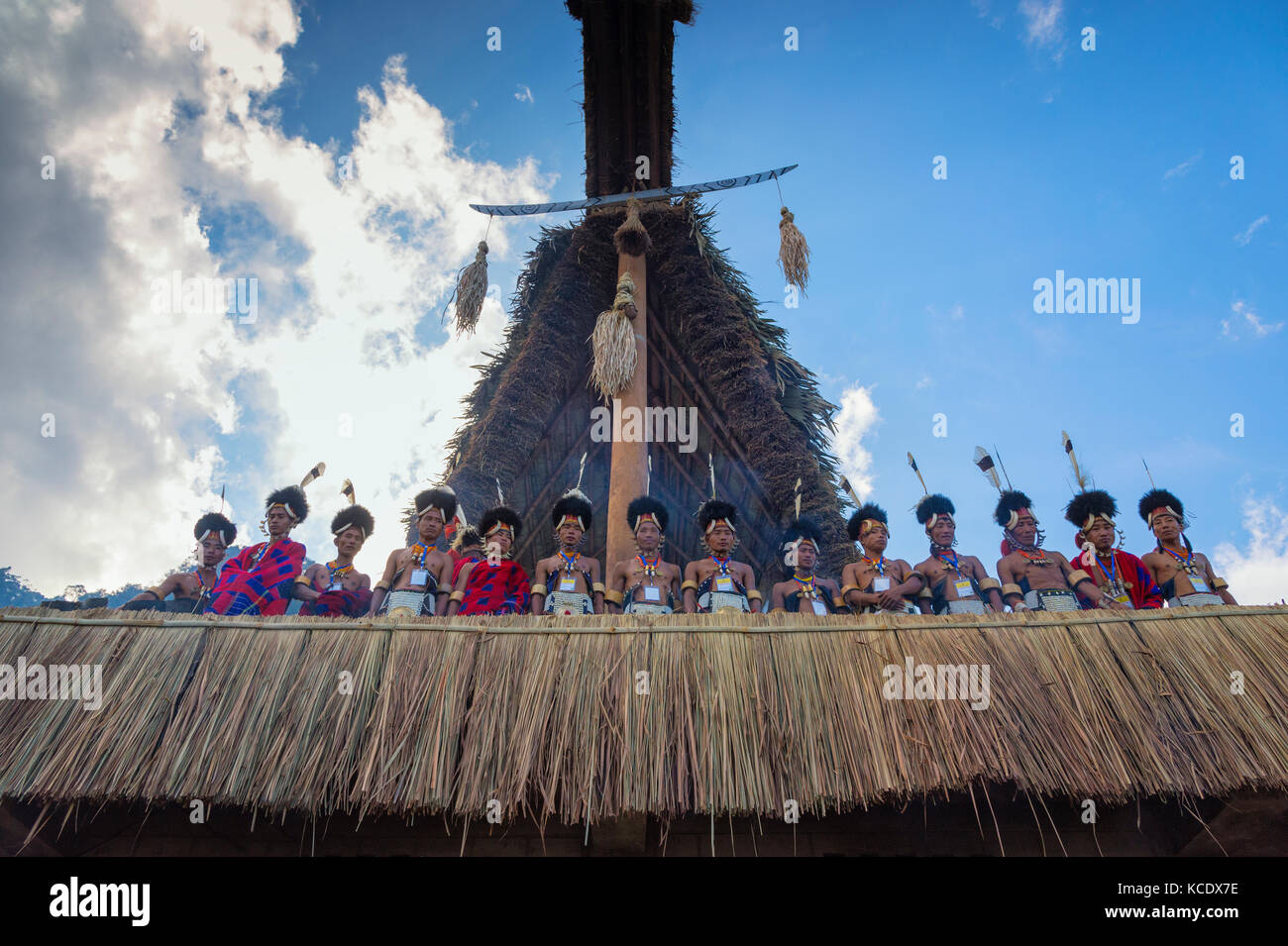 Naga tribal Männer in traditioneller Kleidung auf dem Dach von Morung Haus, Kisima Nagaland Hornbill Festival, Kohima, Nagaland, Indien Stockfoto
