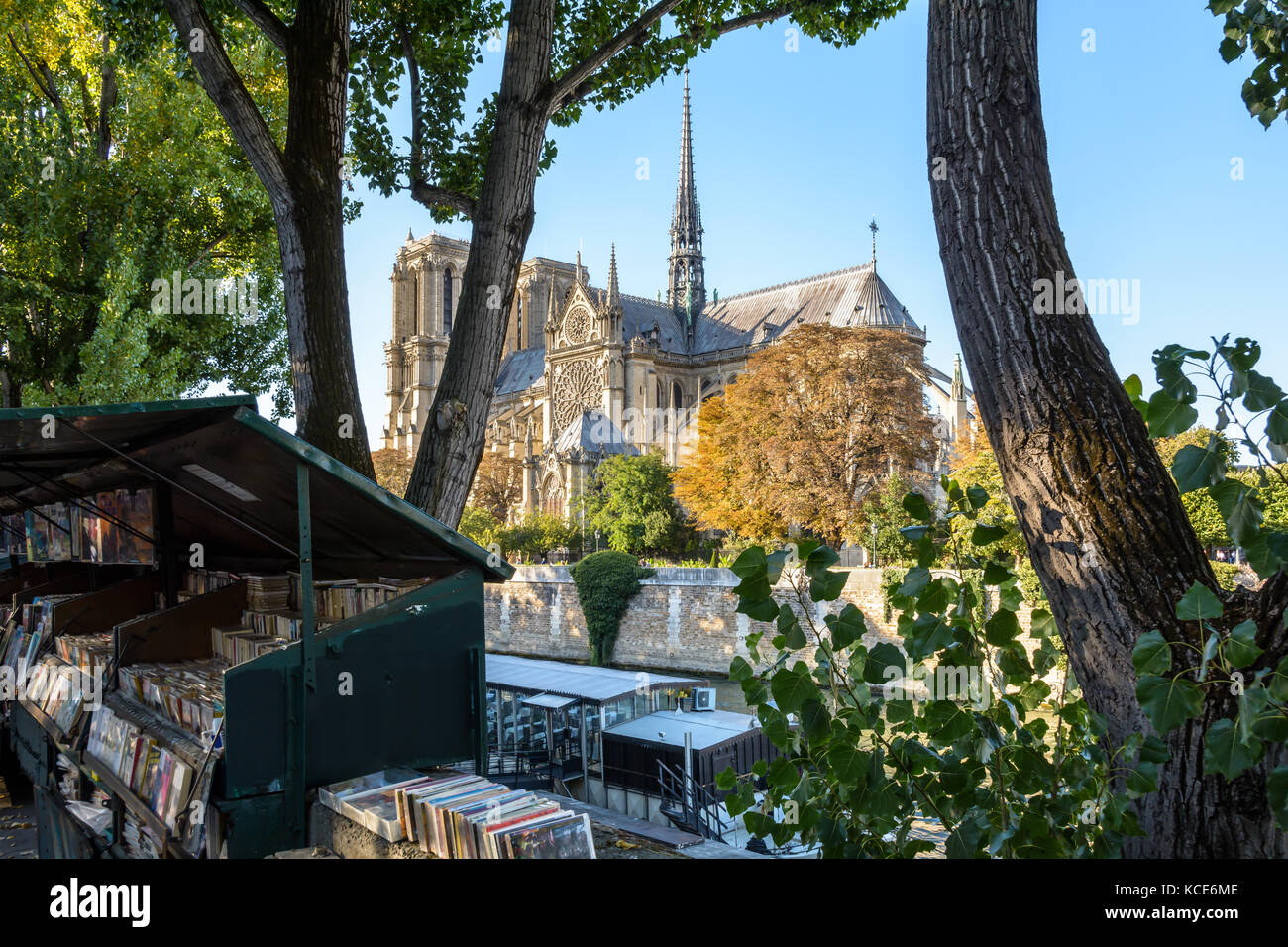 Drei Viertel Rückansicht von Notre-Dame de Paris Kathedrale und der Seine durch einen sonnigen Abend Anfang Herbst mit Restaurant Boot und Buch Stockfoto