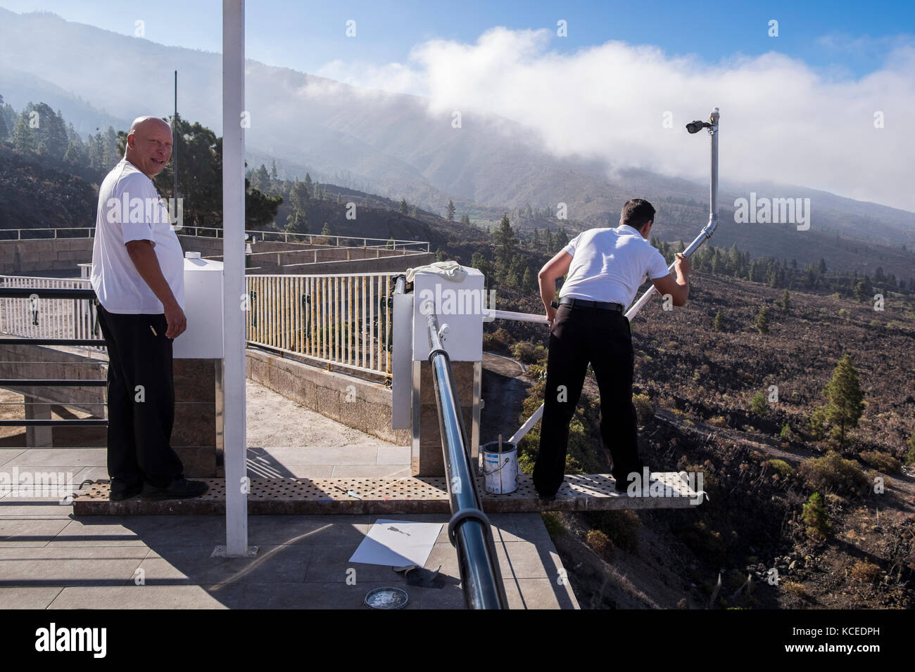 Gefährlich leben, Mann ein Gegengewicht zu einer Metallplatte, auf denen ein anderer Mann Überhängen eine Terrasse eine Unterstützung für eine CCTV-Kamera, Teneriffa, Kanarische Inseln Stockfoto