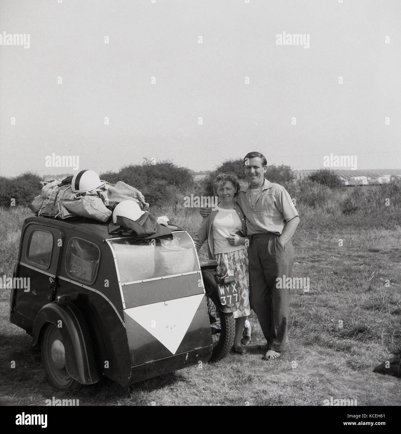 1950, historische, Bild zeigt einen Mann Frau stehen im Freien neben Ihrem Motorrad und Seitenwagen, die sowohl im Innen- als auch auf der Oberseite mit Gepäck und Leinwand Zelt, England, UK geladen wird. Stockfoto