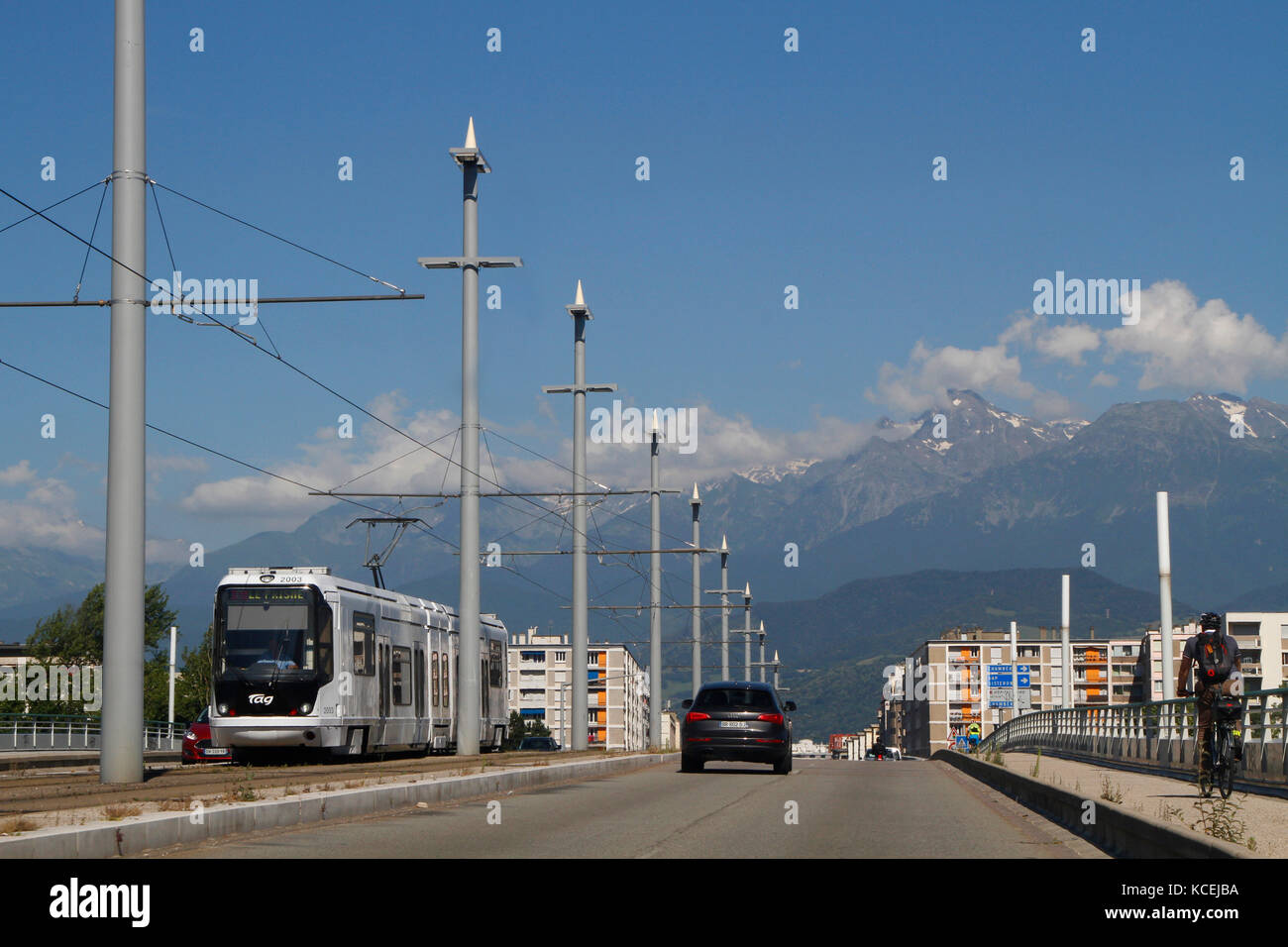 GRENOBLE, FRANKREICH, 4. Juli 2016 : EINE Straßenbahn überquert eine Brücke in Grenoble, mit Bergkette im Hintergrund. Stockfoto
