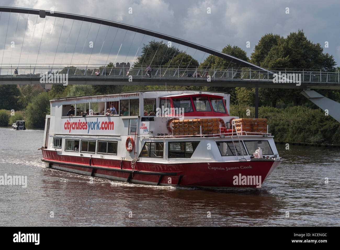Passagiere an Deck genießen sonnige Sommer-Kreuzfahrt, Segeln auf dem Fluss Ouse an Bord City Cruises Boot, vorbei unter Millennium Bridge - York, England, Großbritannien Stockfoto