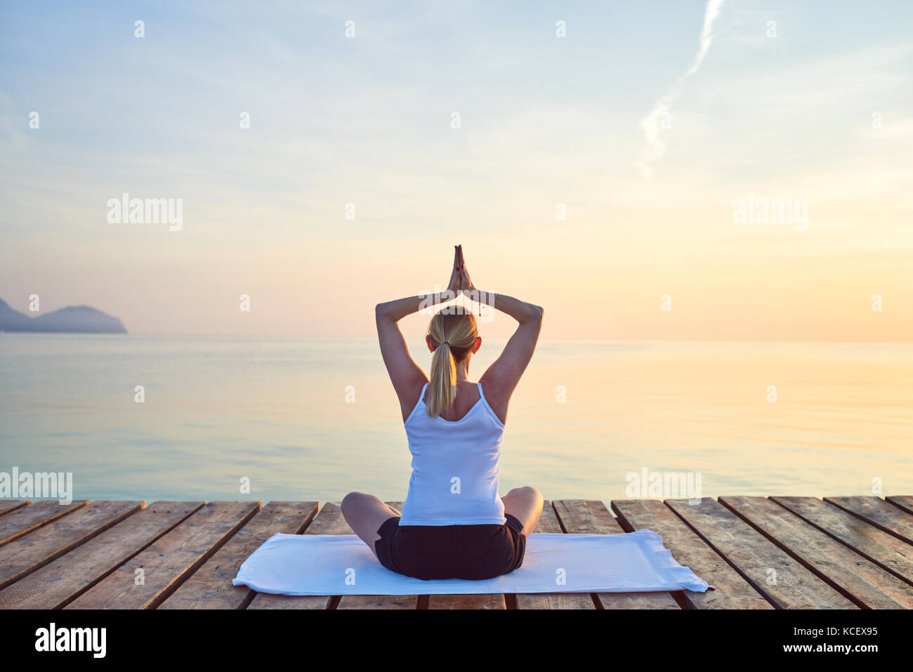 Ansicht der Rückseite des junge Frau saß auf dem Handtuch Üben Yoga von Meer bei Sonnenuntergang Stockfoto