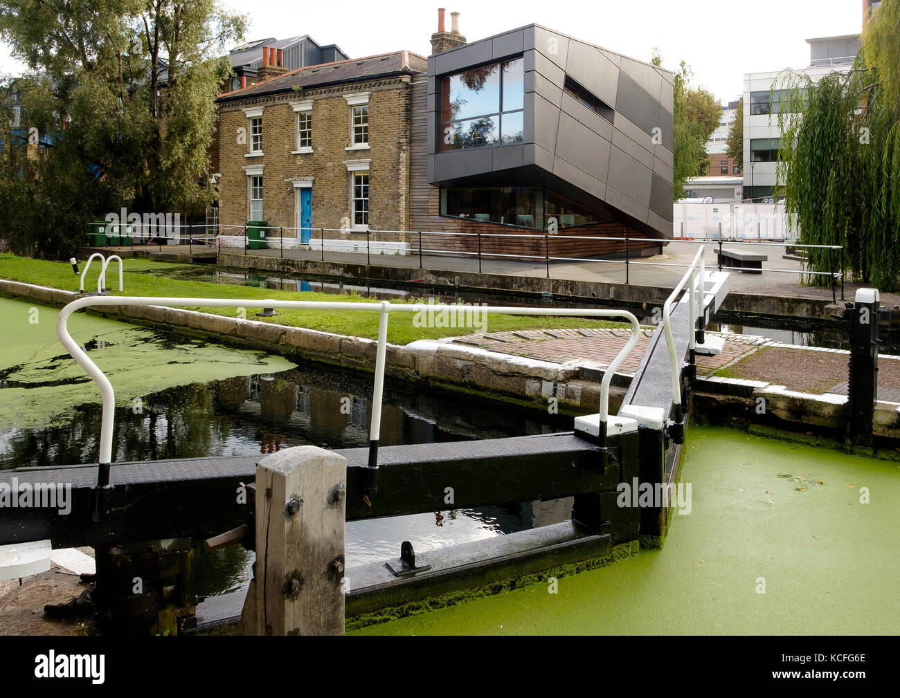 Am Mile End Lock on the Regents Canal, London, bildet die moderne Erweiterung der Lock Keeper's Cottages das Graduate Center für das Queen Mary College Stockfoto