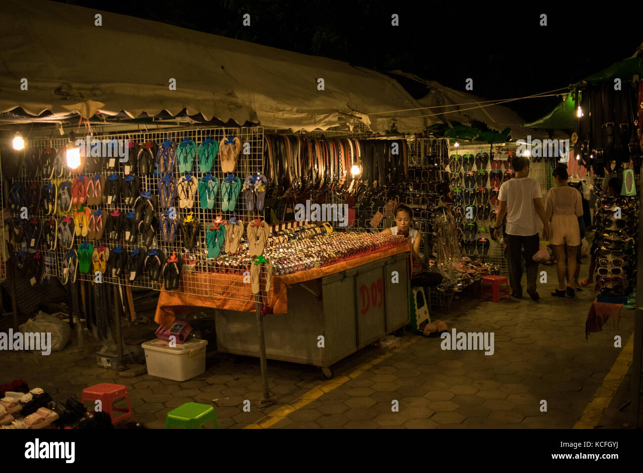 Eine in Phnom Penh nacht Marktstand, Verkauf von verschiedenen Accessoires wie Gürtel, Flip Flops und Uhren. Warten auf Kunden. Kambodscha, Se Asien Stockfoto