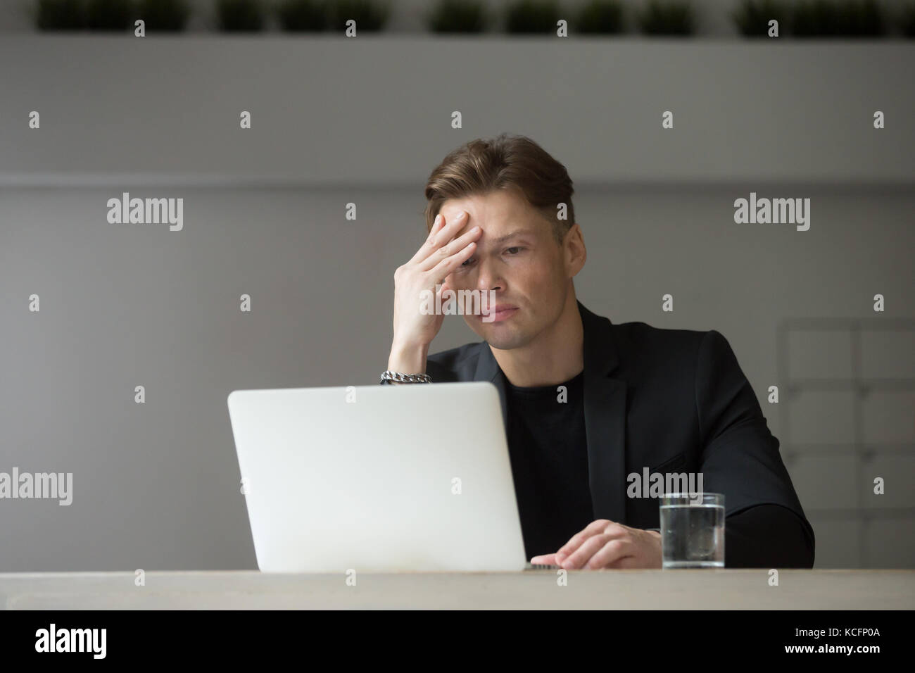 Erschöpft Geschäftsmann am Laptop mit der Hand auf seine Stirn. Project Manager müde von der hohen Arbeitsbelastung, nicht glücklich negativen finanziellen sehen investieren Stockfoto