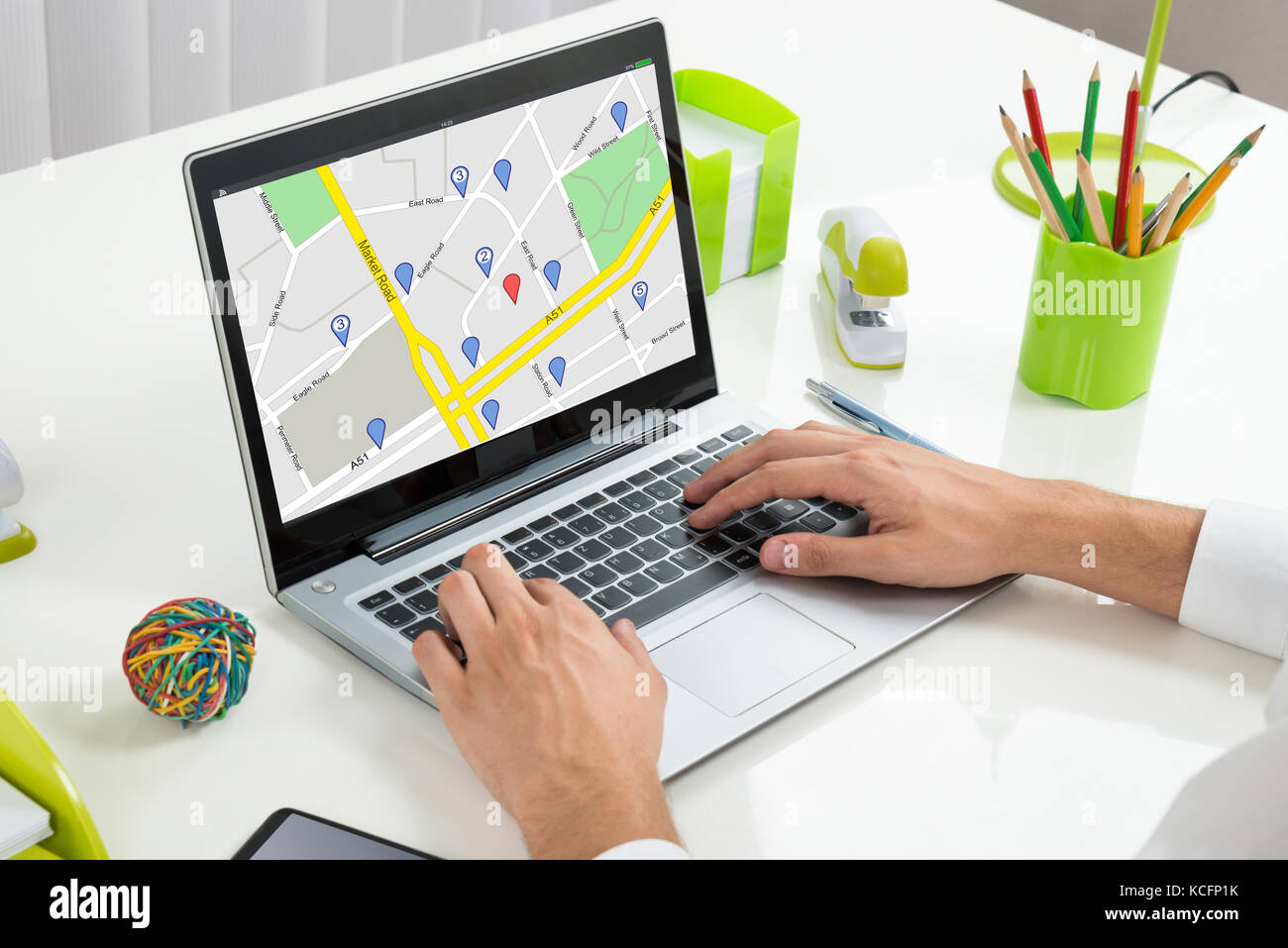 Nahaufnahme einer Person mit Hilfe der GPS-Karte mit Navigation Zeiger auf dem Laptop im Büro Stockfoto