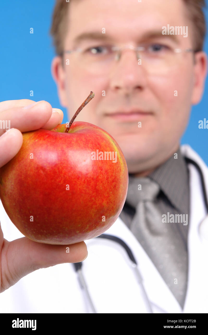 Arzt hält roten Apfel in der Hand, sein Gesicht Stockfoto