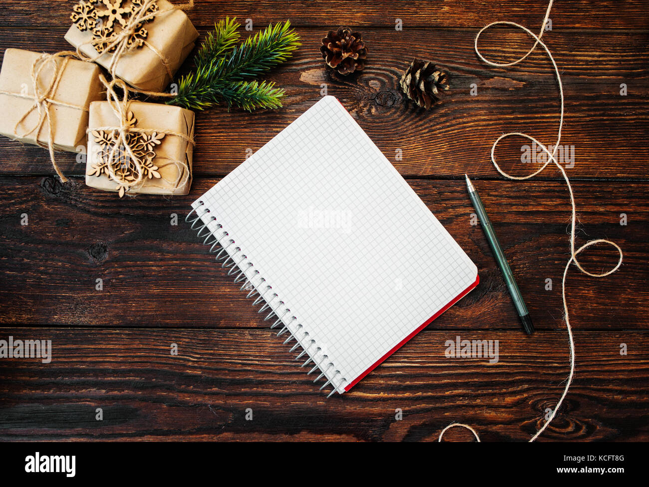Weihnachten Zusammensetzung der Geschenk Kraftpapier Boxen und Holzspielzeug, Mais und Hinweis mit Stift auf hölzernen Hintergrund Stockfoto