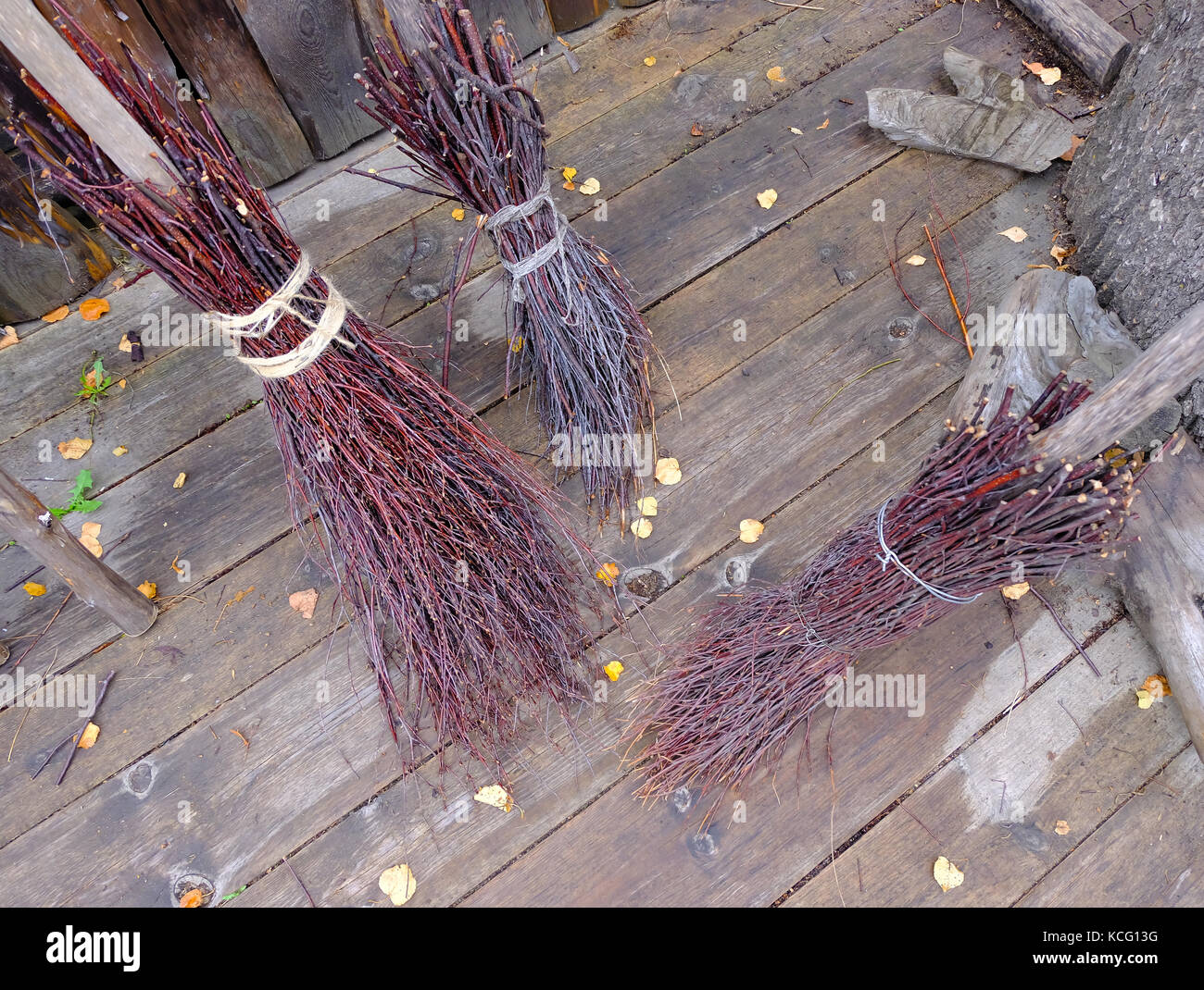 Drei Hexen Besen auf dem Holzboden im Herbst. Aufrechterhaltung der Sauberkeit im Haus und Hof, vintage Los für die Reinigung. Stockfoto