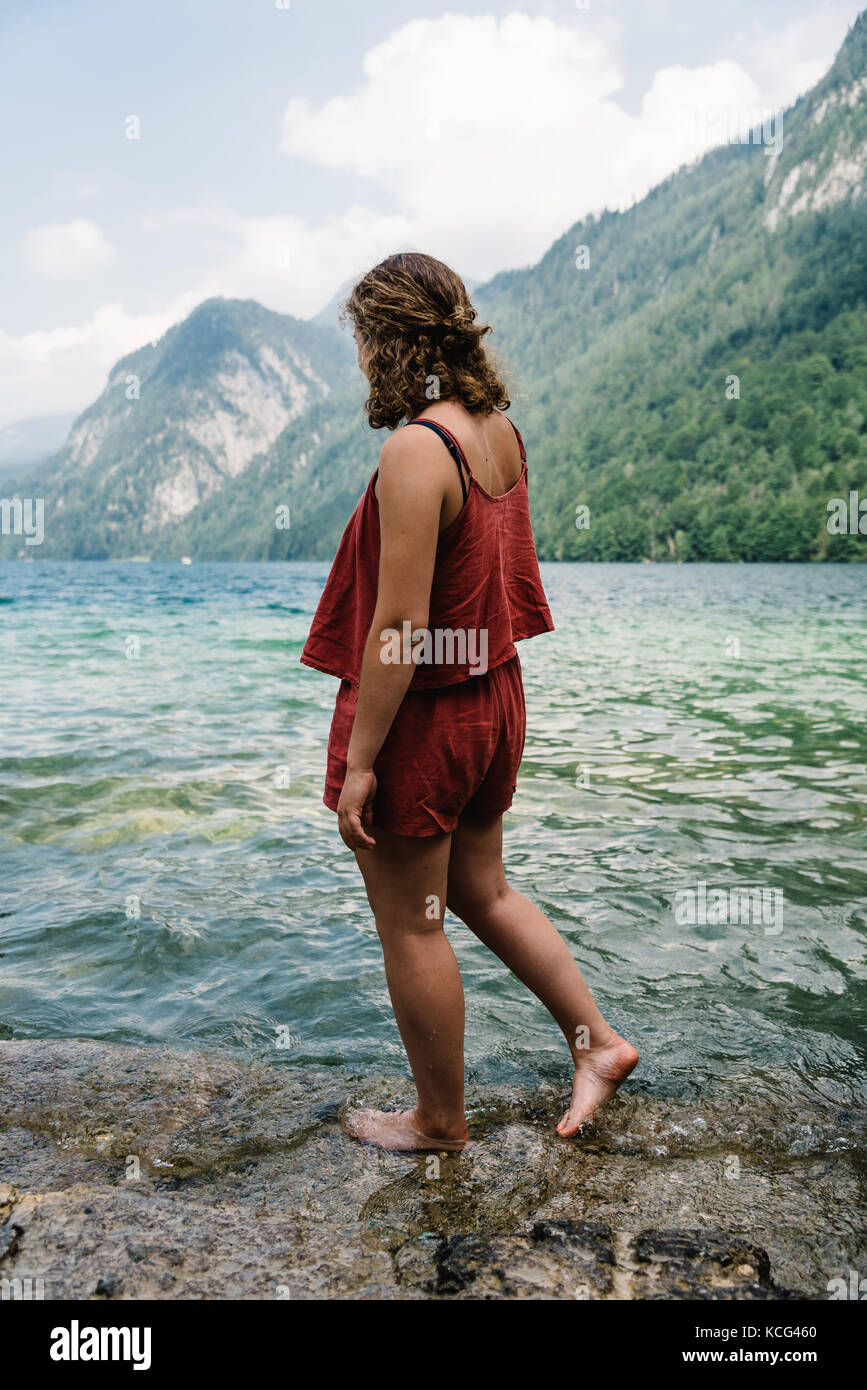 Barfuß junge Frau steht auf Felsen mit Blick auf See Stockfoto