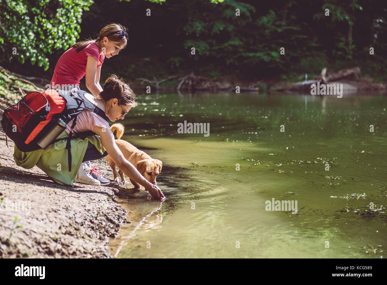 Mutter und Tochter mit Hund Ruhe am See Stockfoto
