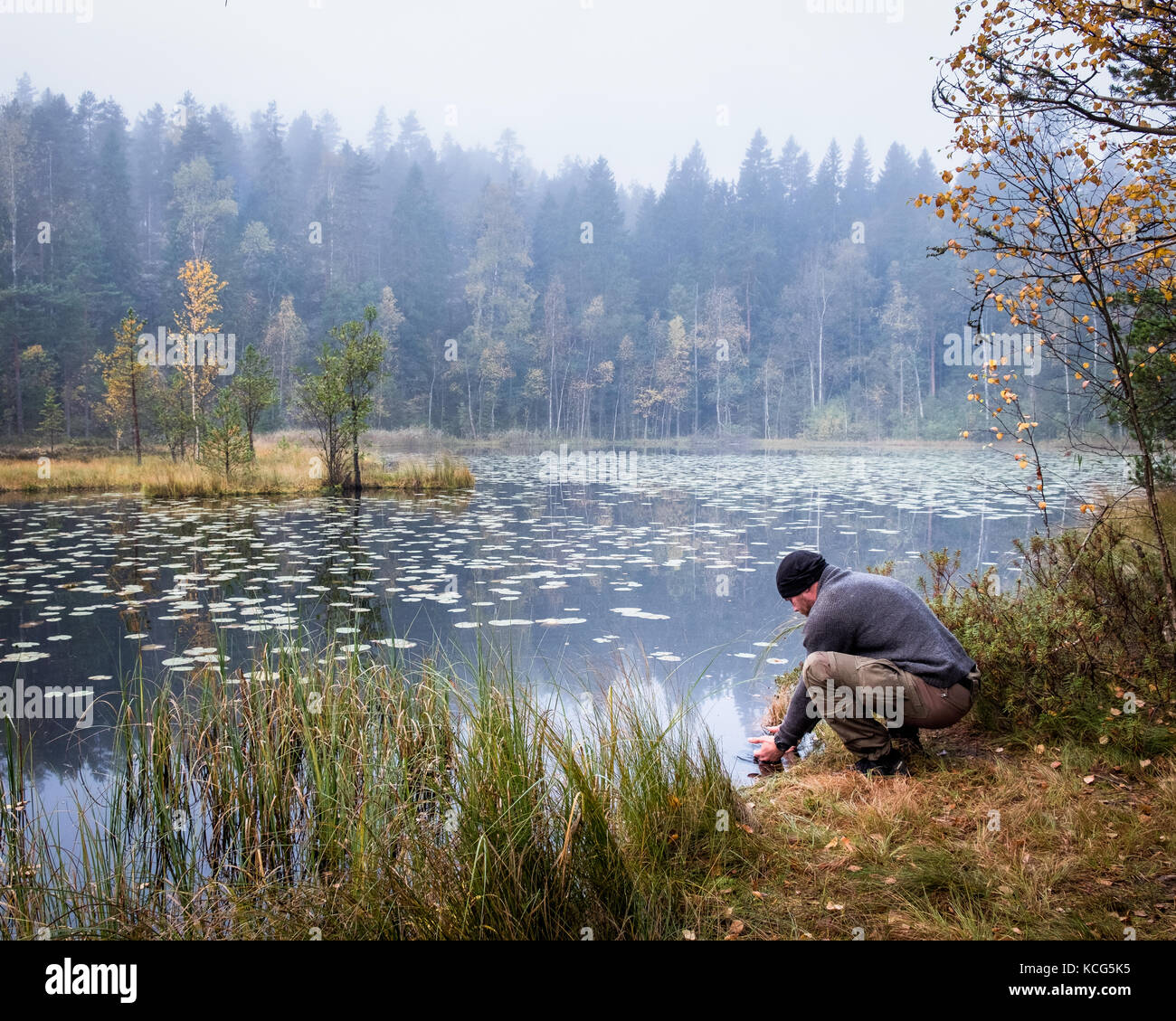 Wanderer waschen sein Angesicht zu Herbst morgen im Nationalpark, Finnland Stockfoto