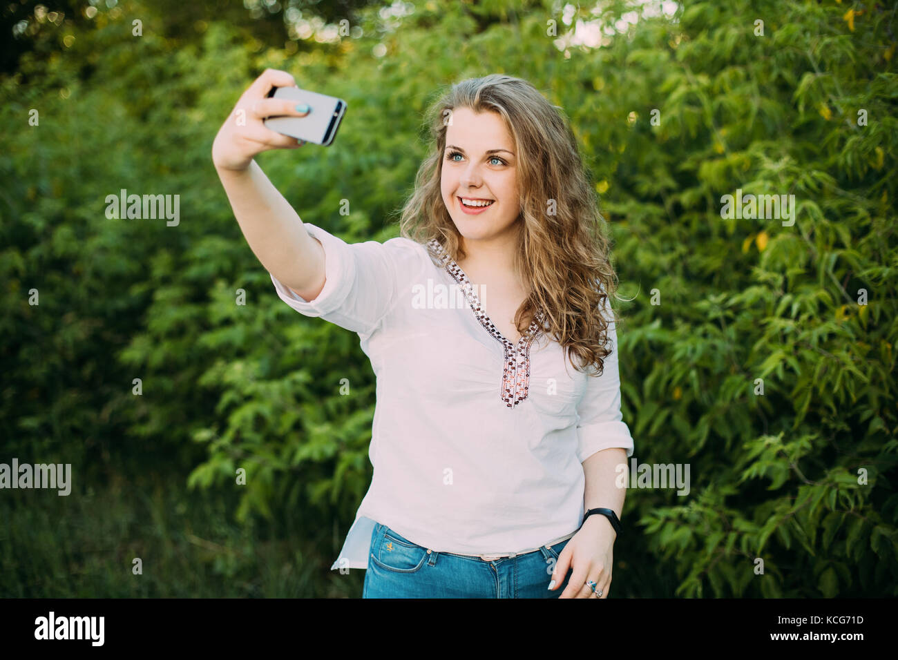 Junge schöne ziemlich Plus size kaukasische Mädchen Frau in weißen Bluse das Leben genießen gekleidet, lächelnd, Spaß und unter selfie Foto auf dem Smartphone Stockfoto