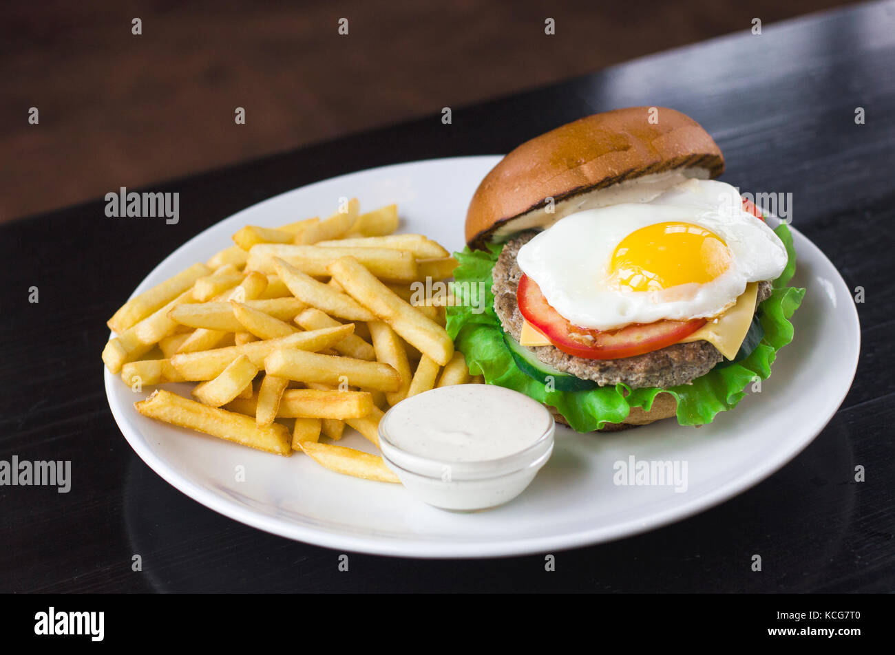 Fleisch Burger mit Ei, Sauce und Pommes frites auf der blsck Tabelle Stockfoto