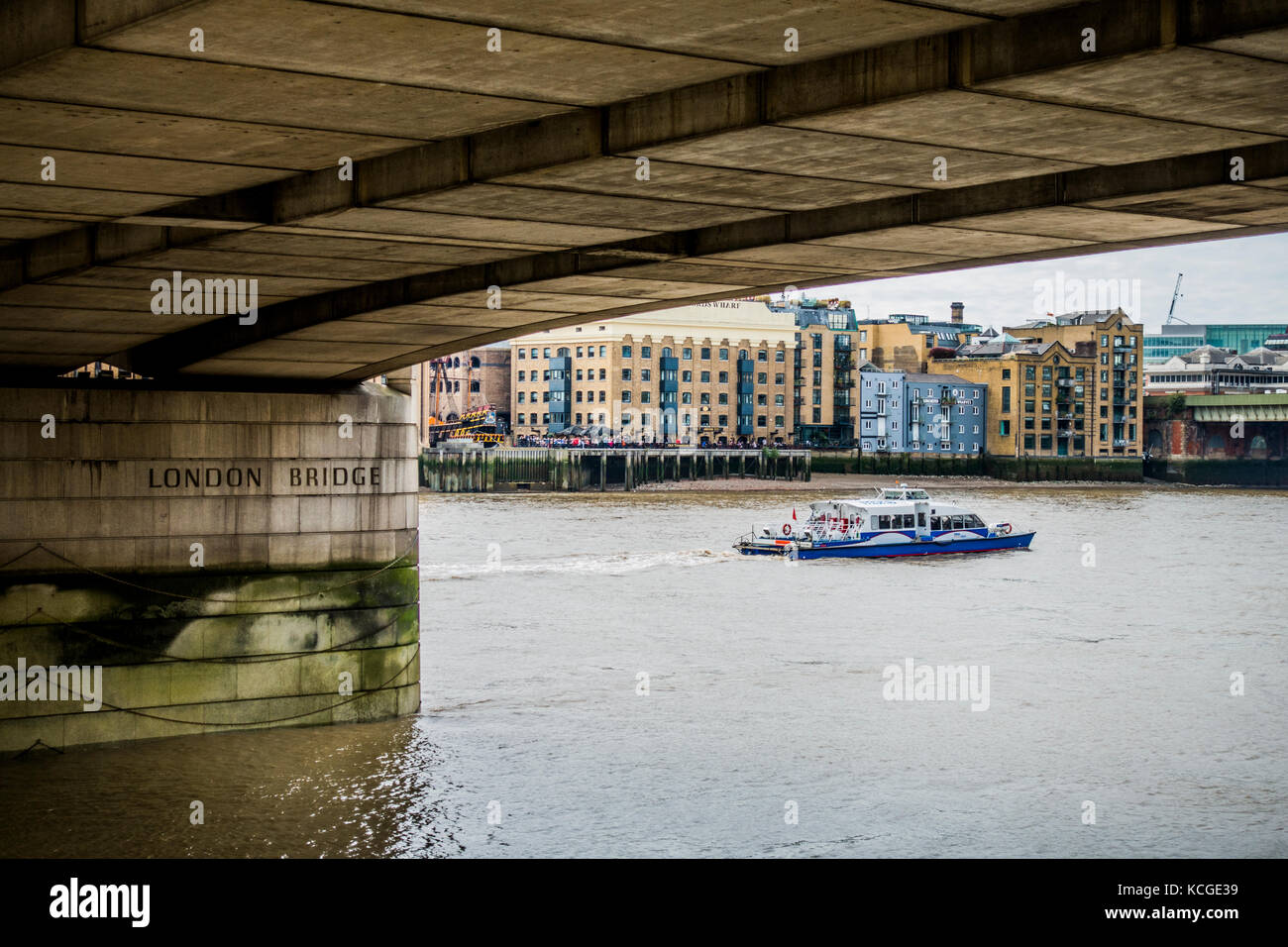 Eine sightseeing Boot segeln auf der Themse, von Apartment Gebäuden übersehen, und der Unterseite der London Bridge, England, UK. Stockfoto