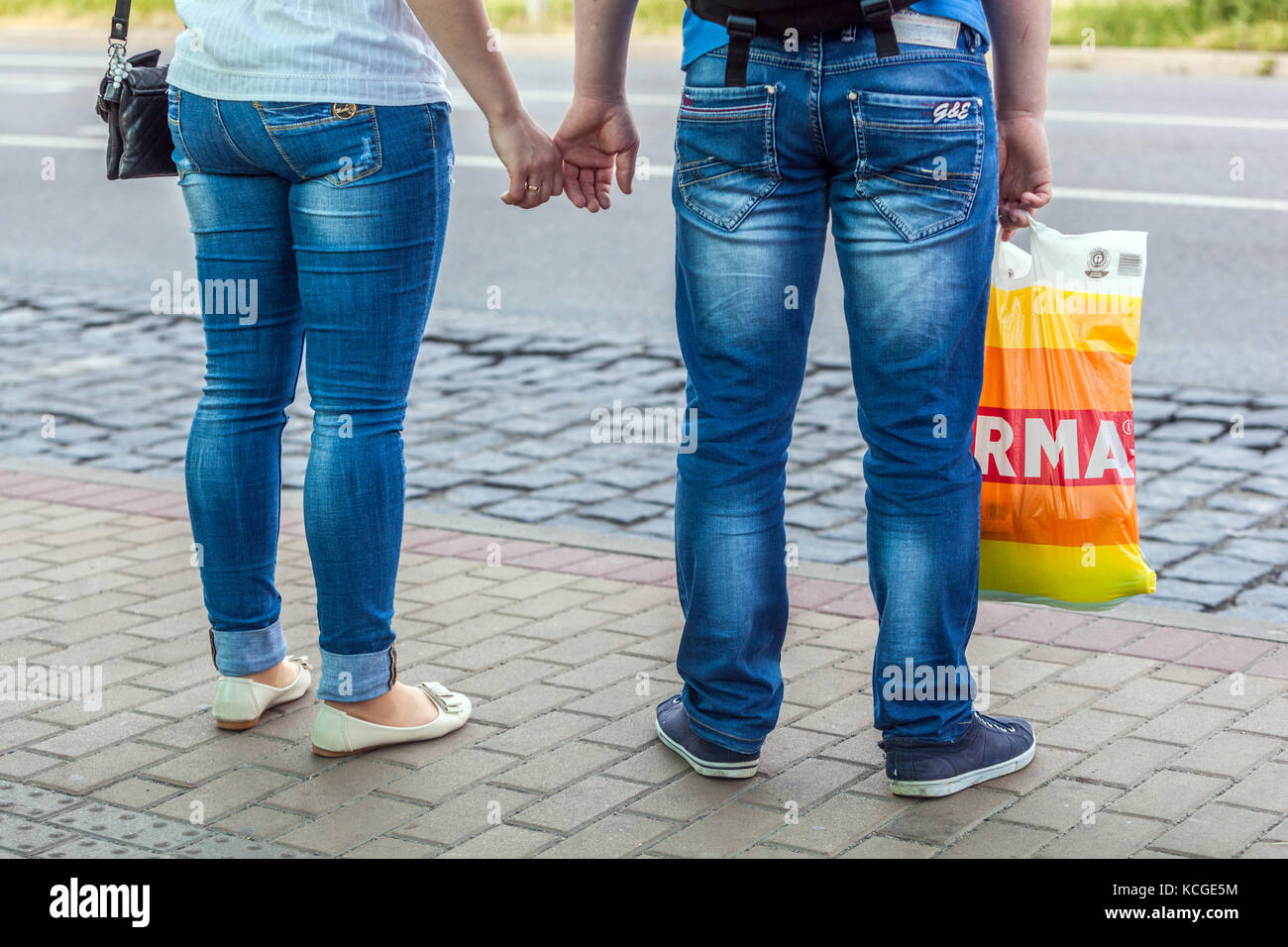 Die Leute, die die Hände halten, sind hinten, ein Mann, der eine Plastiktüte hält, Jeans Street Style Frau Mann Jeans Stockfoto