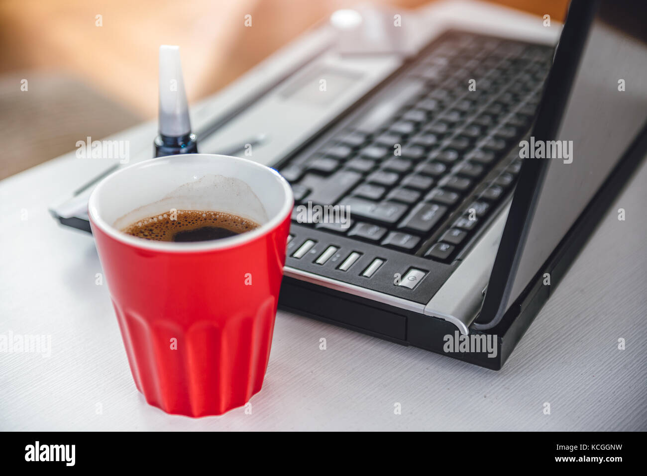 Rote Kaffeetasse, Nagel Lack und Laptop auf dem Tisch Stockfoto