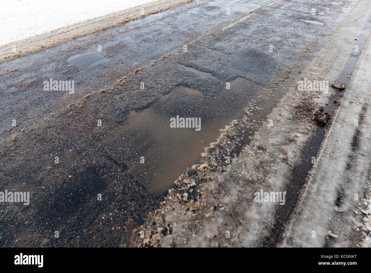 Eine asphaltierte Straße im Winter. das Foto in einem Winkel Nahaufnahme war und auf der Straße die Tracks aus den Autos gebildet wurden und die Grube Stockfoto