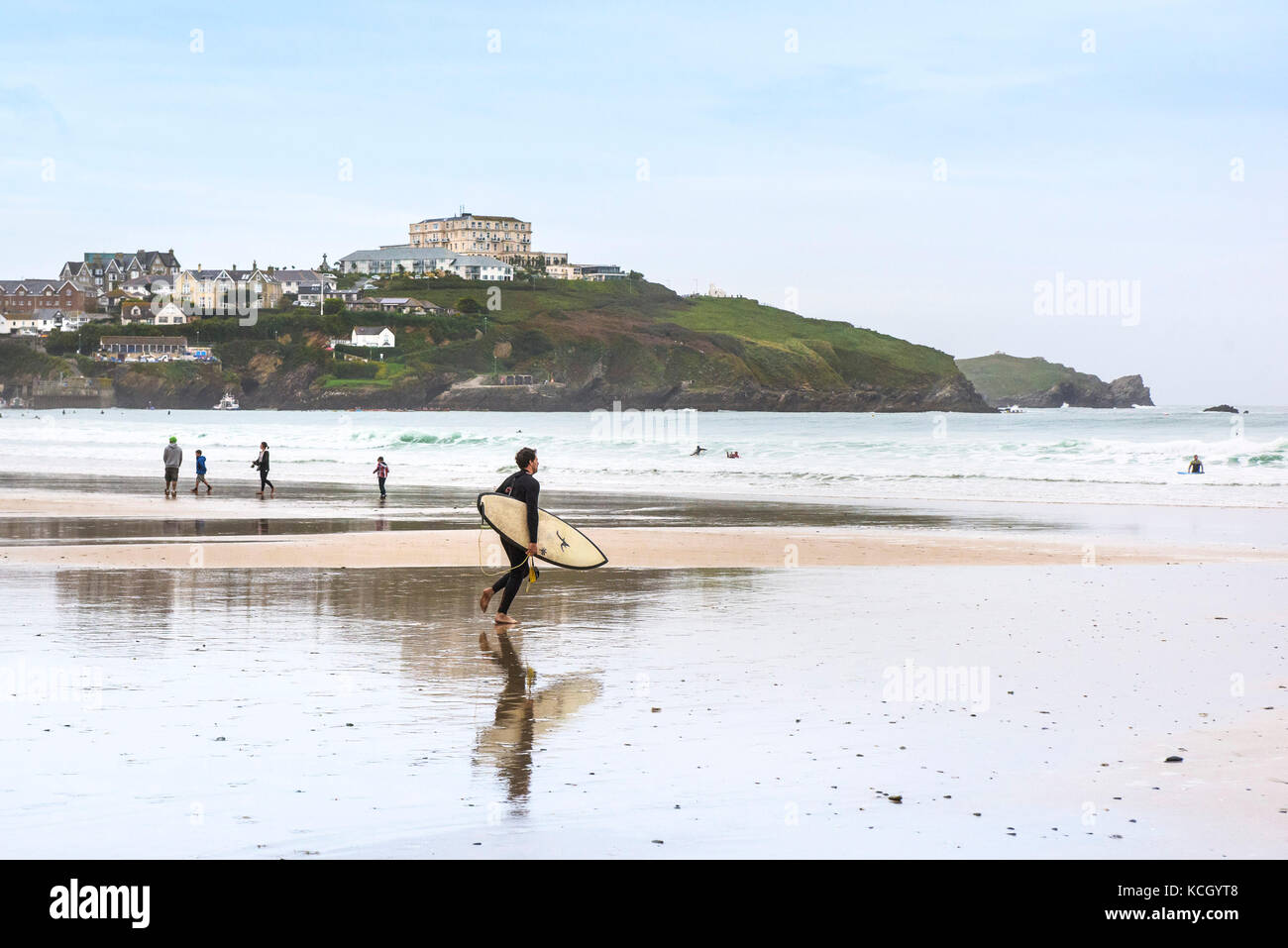 Surfers in Cornwall - ein Surfer, der am Great Western Beach in Newquay, Cornwall, über den Strand läuft. Stockfoto