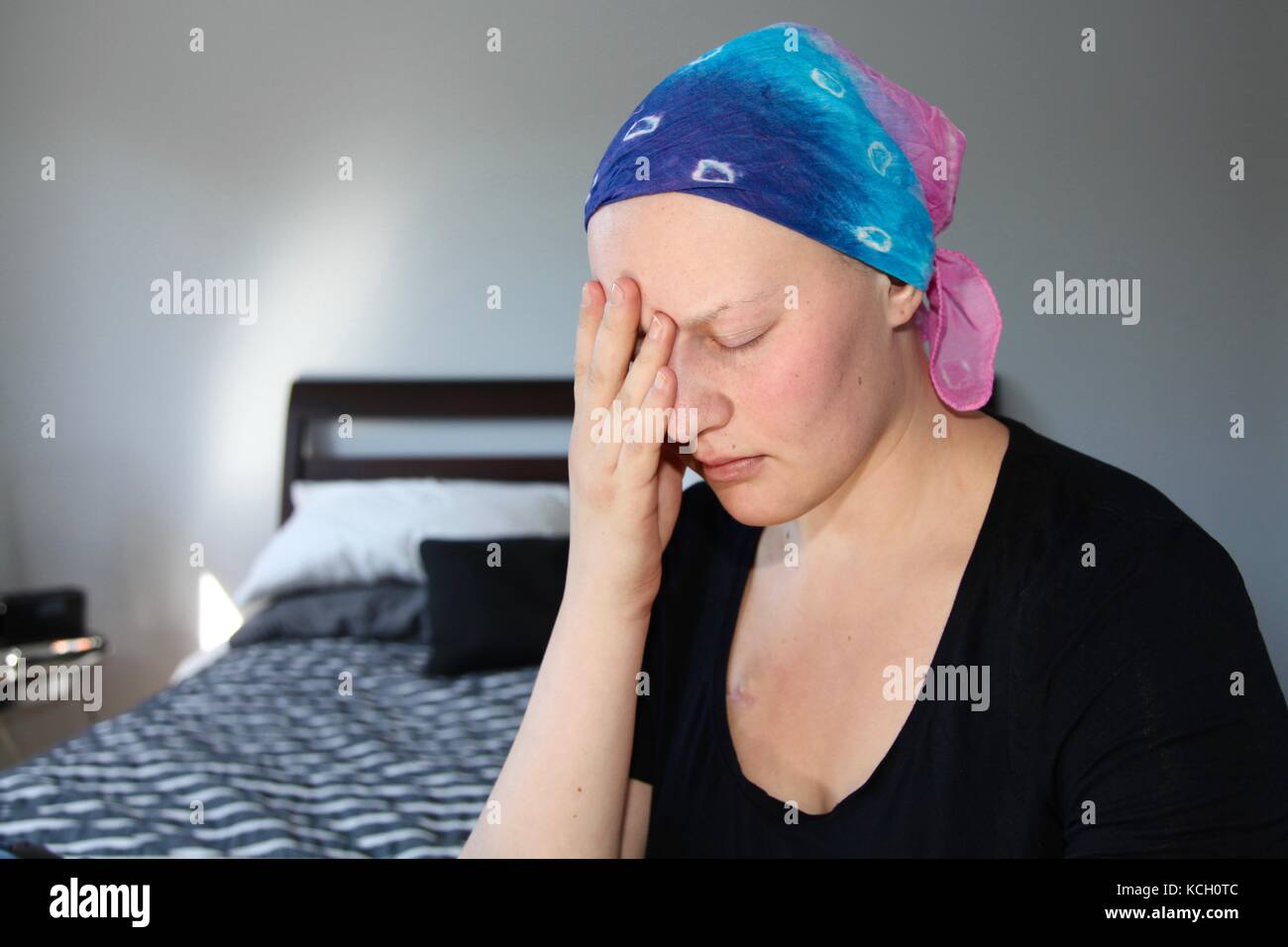 Junge Krebspatienten in einem Kopftuch hält Kopf in den Händen, mit Stress Stockfoto