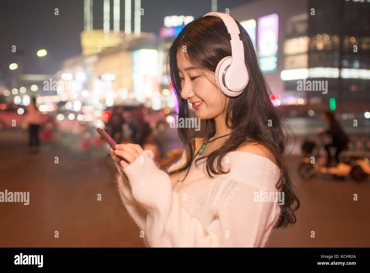 Die schönen Frauen, Mobiltelefone zu benutzen, um Musik zu hören Stockfoto