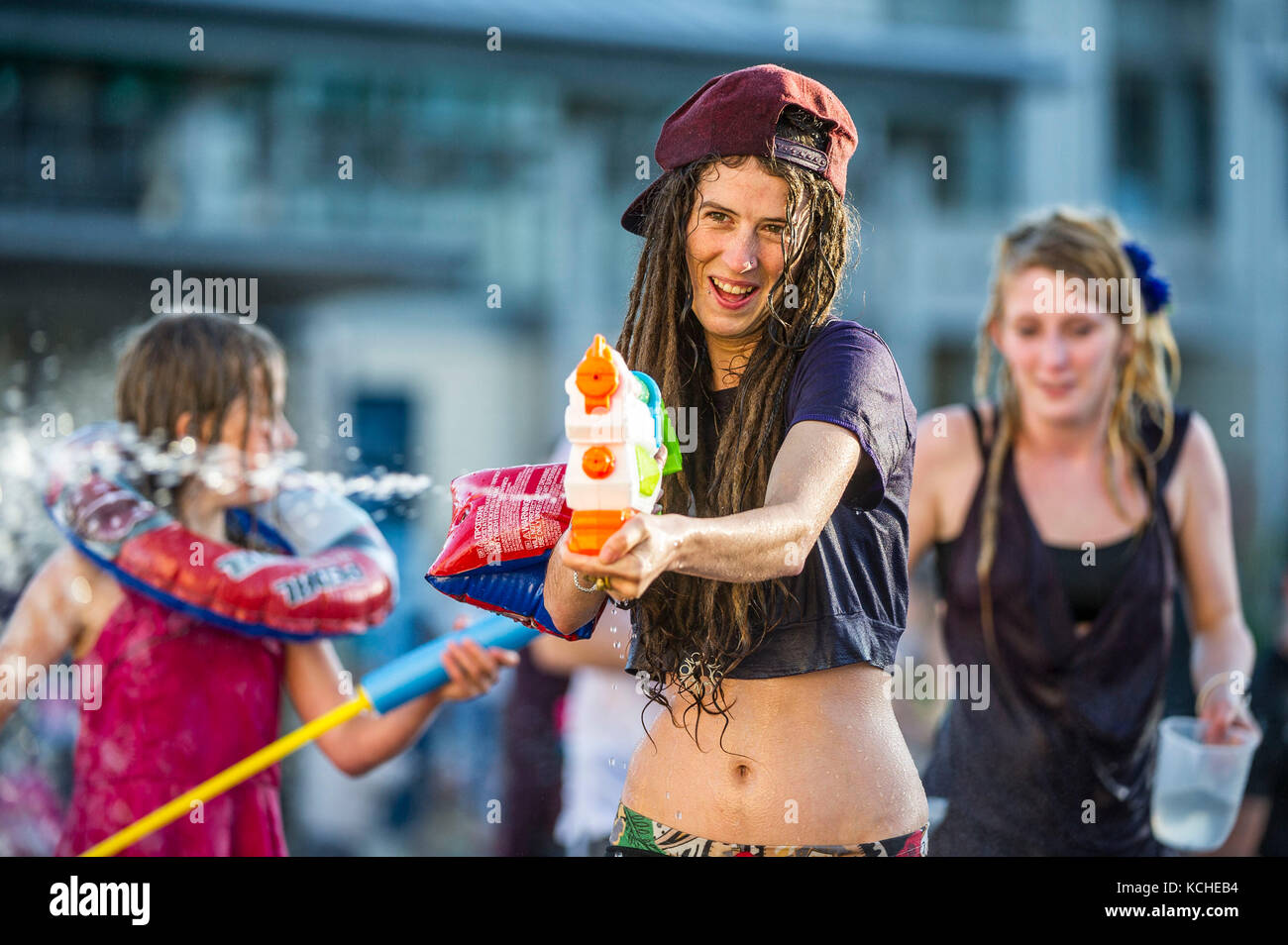 Eine Frau mit Dreadlocks feuert eine Wasserpistole bei einer Liebe wasser Kampf in Bristol Millennium Square. Stockfoto