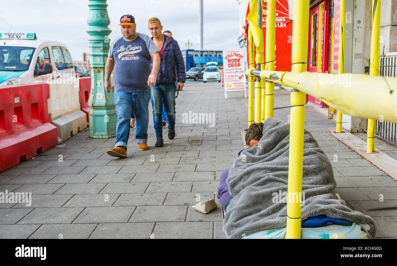 Menschen schlafen auf den Straßen von Brighton, East Sussex, England, UK, mit Menschen zu Fuß hinter ihn zu ignorieren. Stockfoto