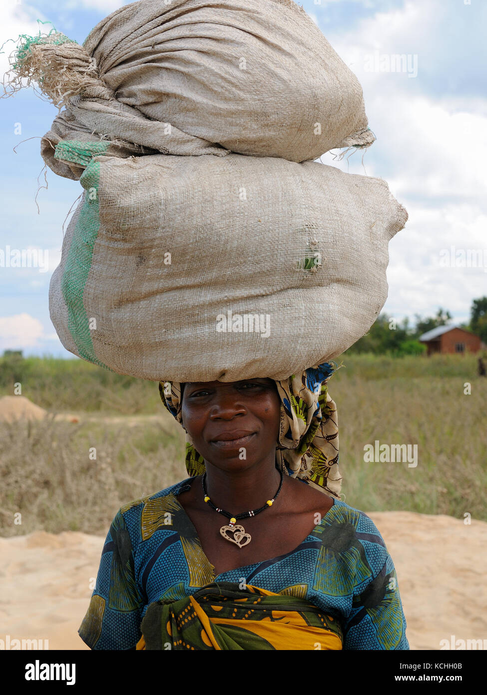 Ikola, Tansania - Mai 07: afrikanische Frau, die auf ihrem Kopf zwei Taschen von Korn in den Tanganjika-see in Tansania, ikola im Mai 07, 2013 Stockfoto