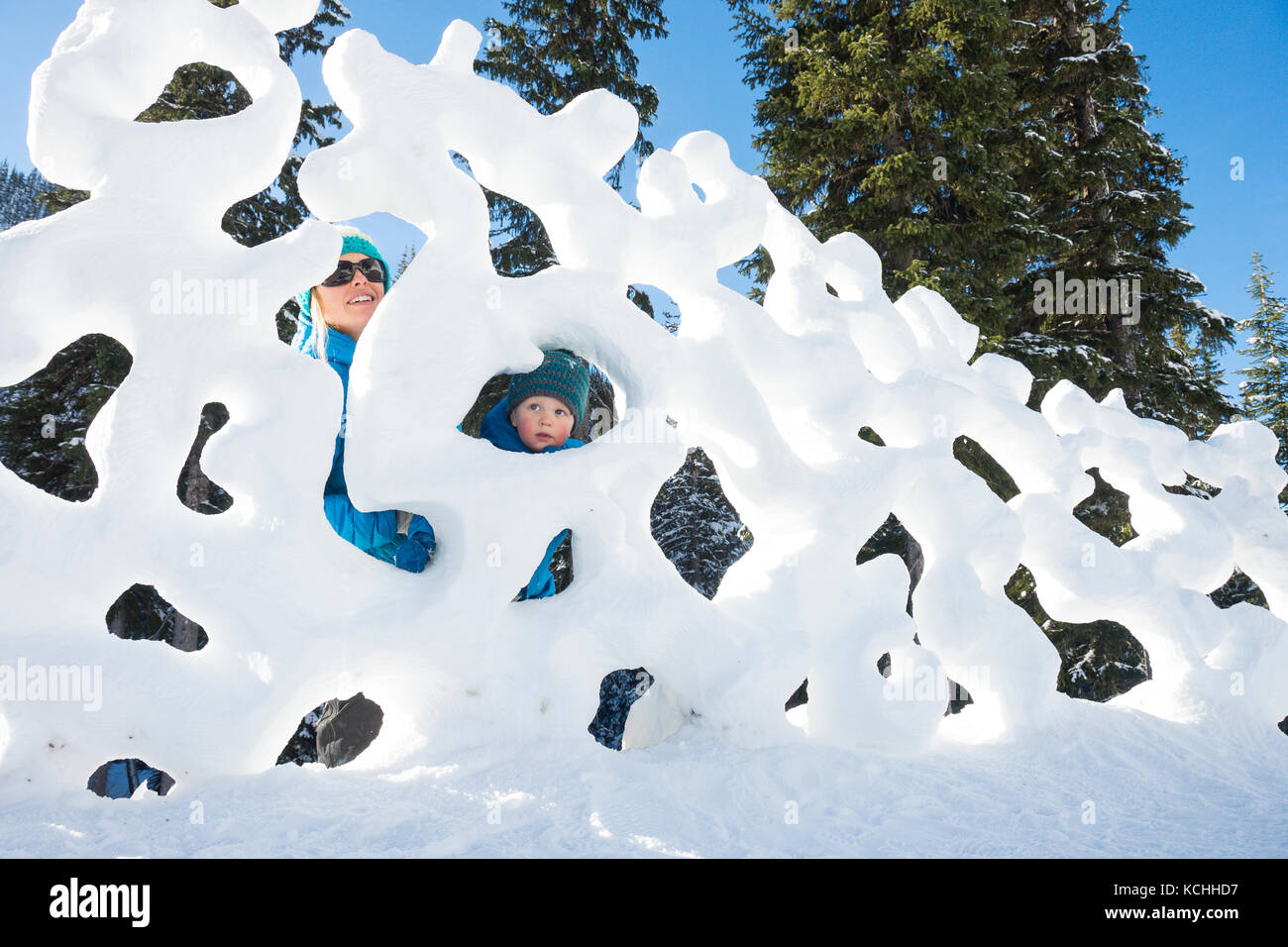 Ein Junge und seine Mutter spielen in einer interessanten Schnee Skulptur im Winter Karneval Stockfoto