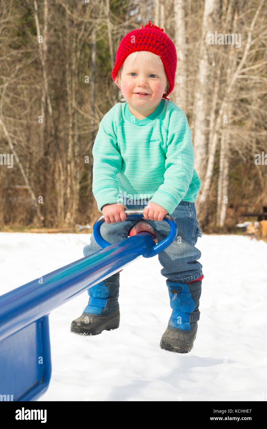 Ein zweijähriger Junge spielt alte auf einem teeter-totter im Winter Stockfoto