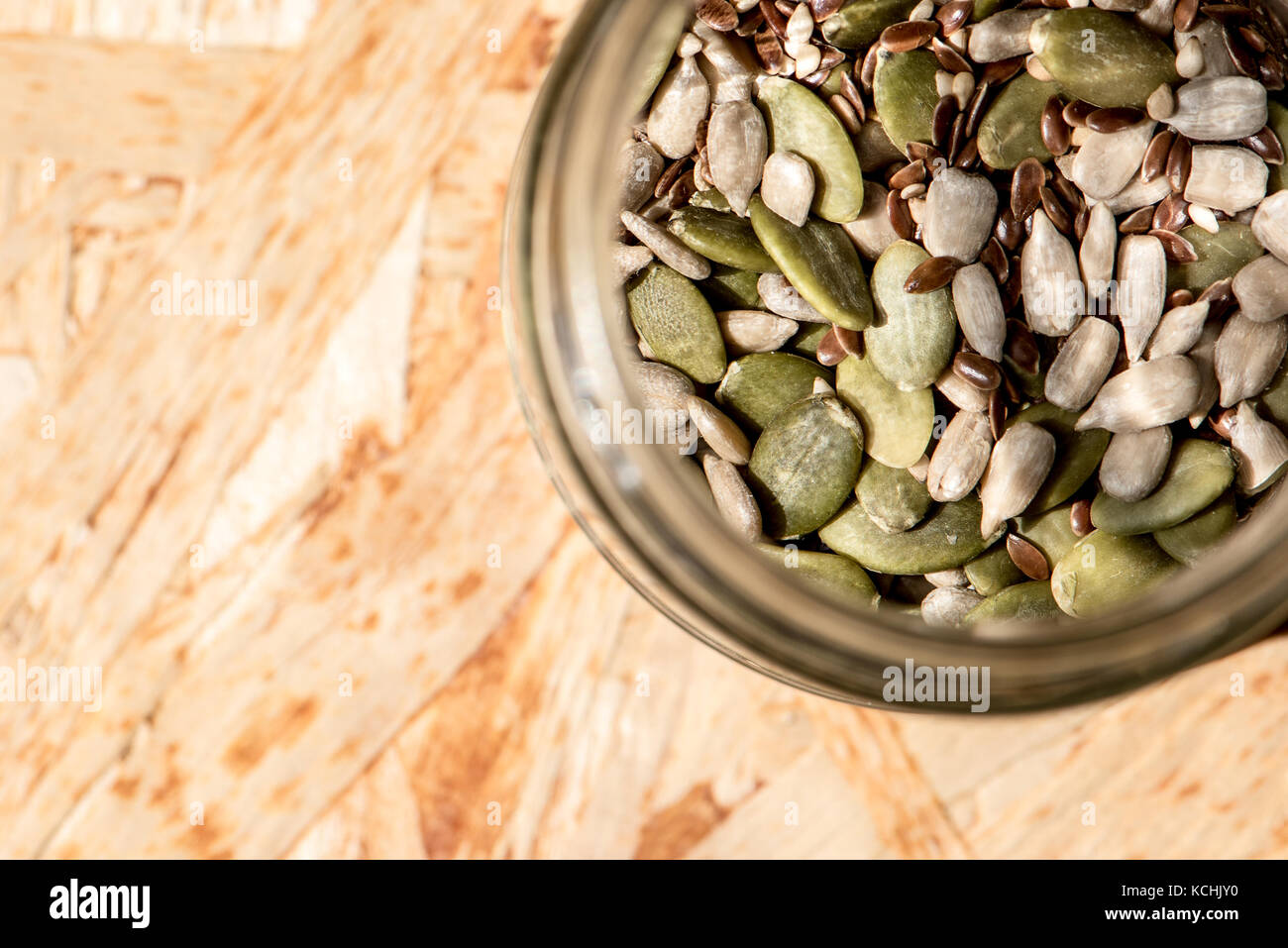 Mason jar voller Samen, gesunde Rohkost, Mix aus Flachs, Sesam, Kürbis- und Sonnenblumenkerne Stockfoto