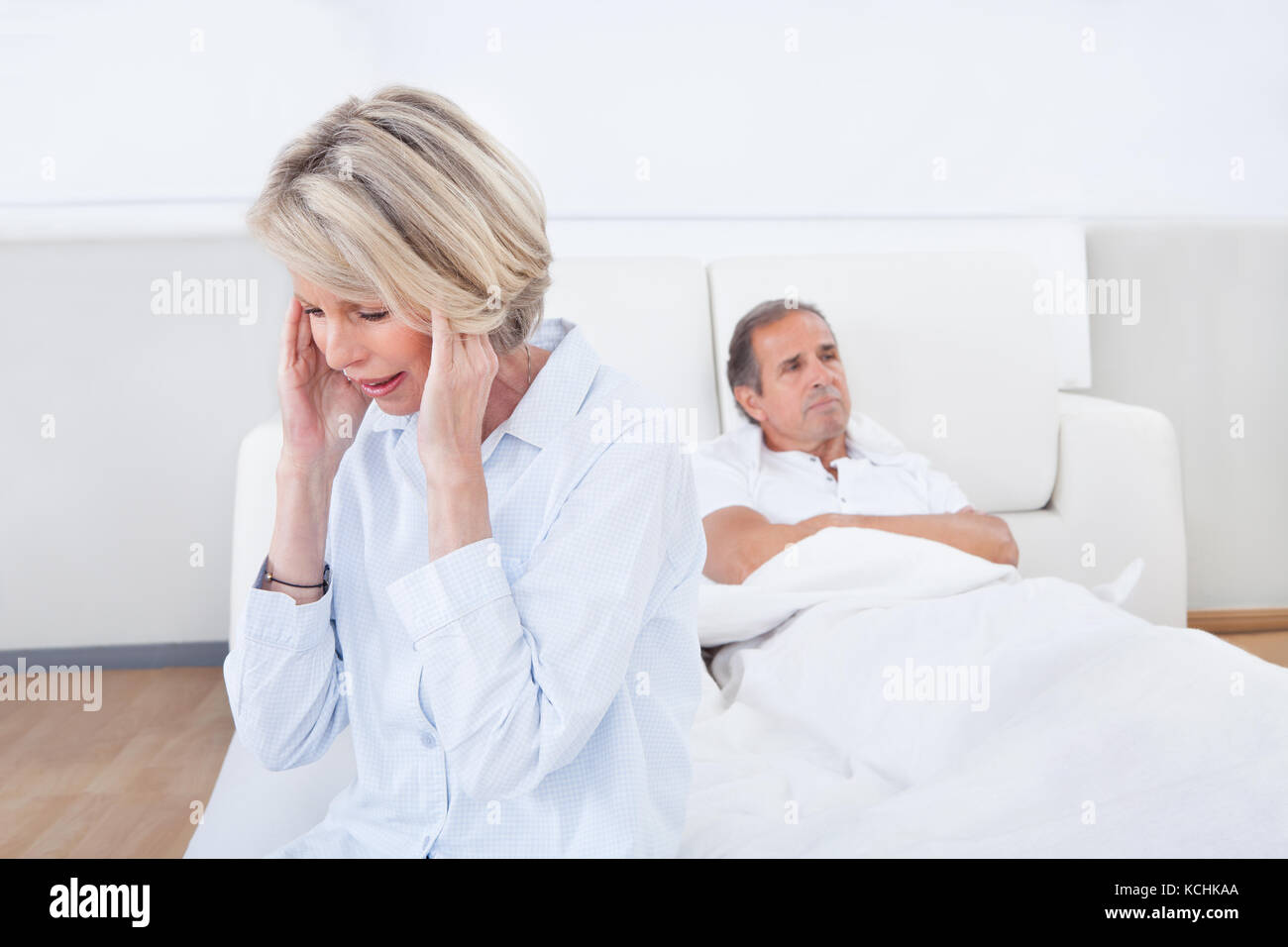 Traurig sitzt am Rand des Bettes vor Mann Frau Stockfoto