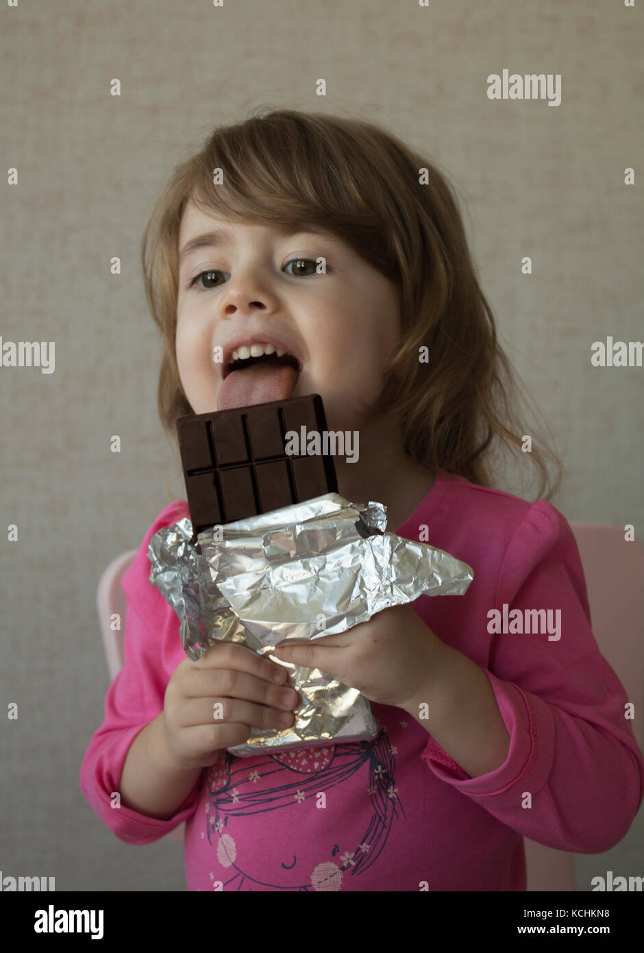 Fröhliches kleines Mädchen Schokolade essen. Stockfoto