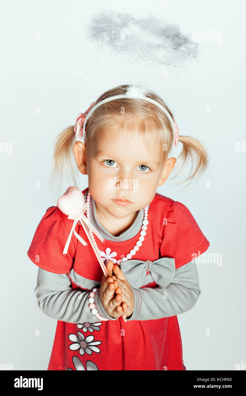 Porträt eines kleinen Mädchens mit einem Spielzeug ein Nimbus auf dem Kopf. Mädchen faßte ihre Hände im Gebet Stockfoto