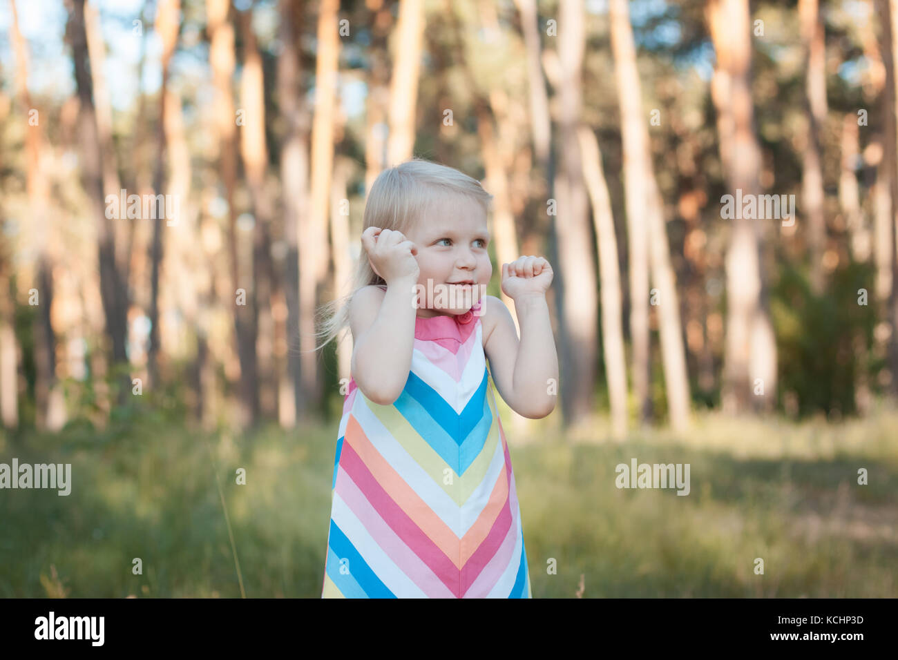 Kleines Mädchen blonde Kind ein buntes Kleid im Wald. Stockfoto