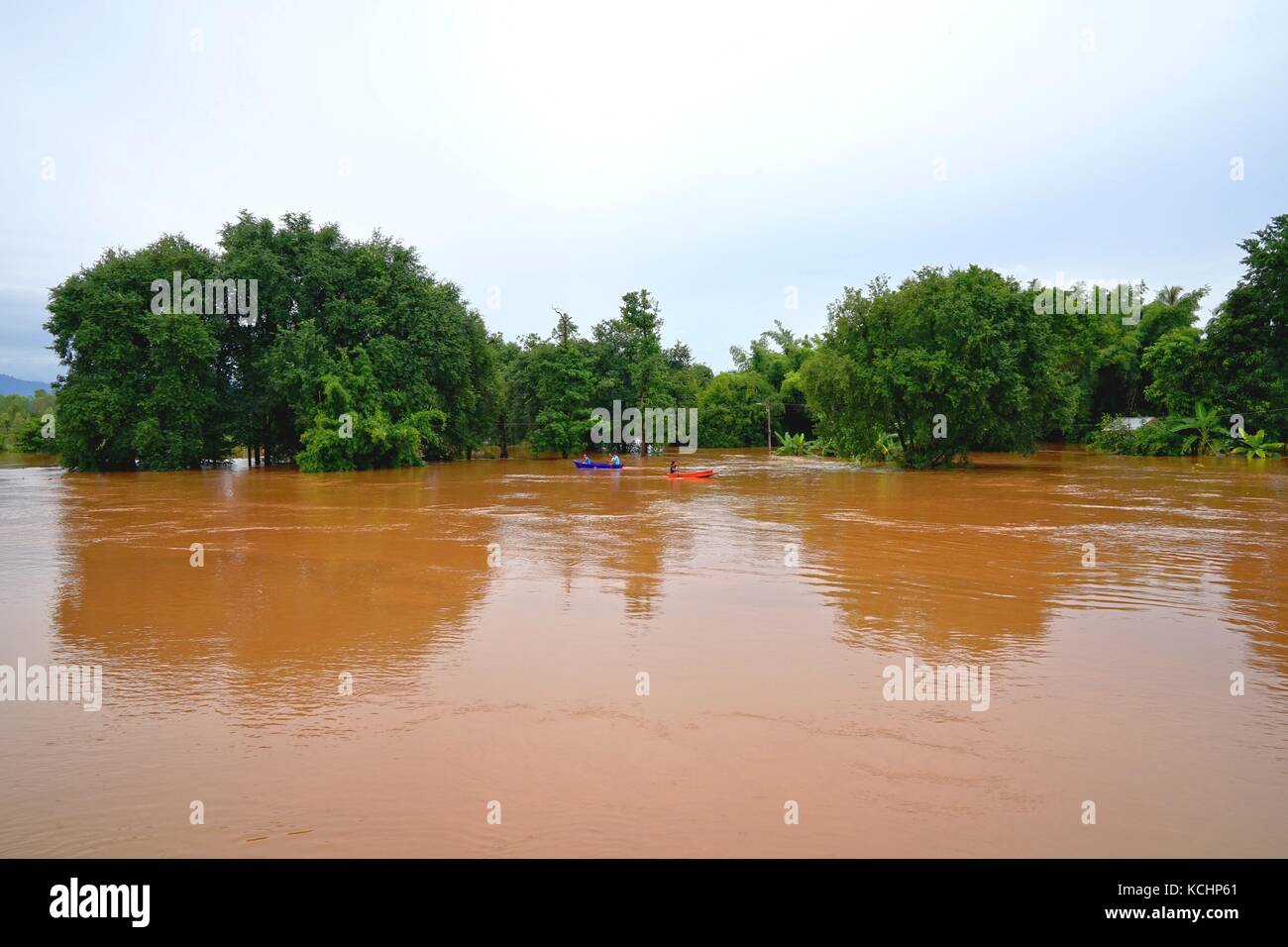 Phitsanulok, Thailand - September 16,2017: Flash Flood von Red trübes Wasser fließt vom Berg aufgrund der sintflutartigen Regenfälle mit Menschen paddeln Boa Stockfoto