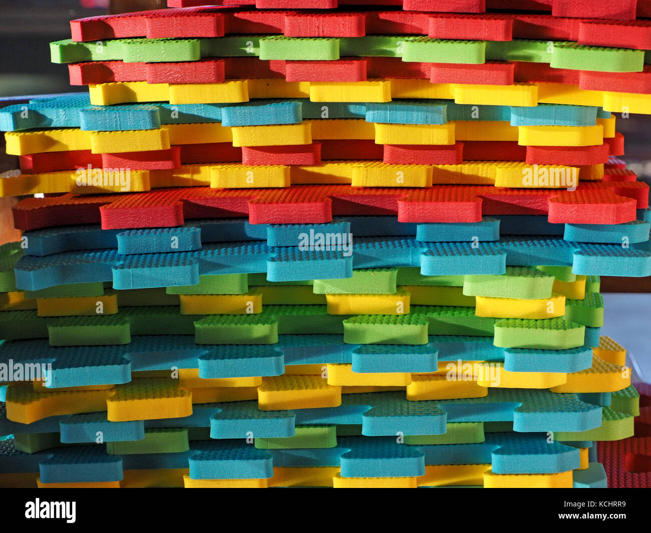 Stapel von mehrfarbigen Verriegelung playmat Panels mit Jigsaw Kanten im hellen Sonnenlicht oblique niedrig Stockfoto