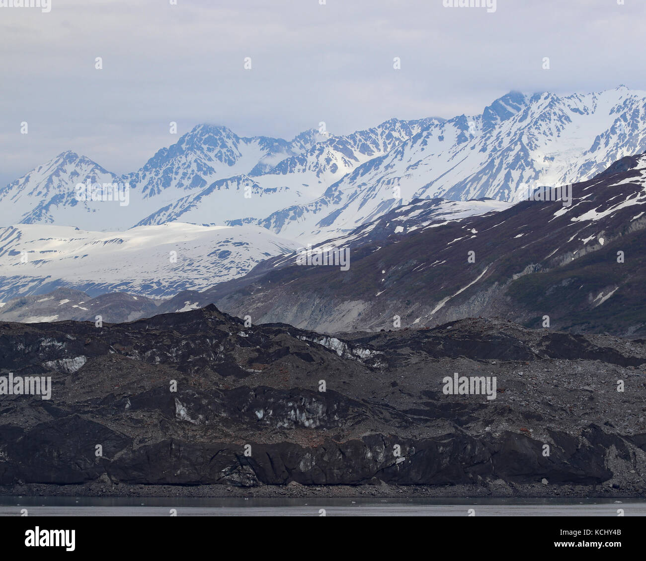 Rocky alaskischen Küste mit Schnee bedeckte Berge in der Ferne Stockfoto