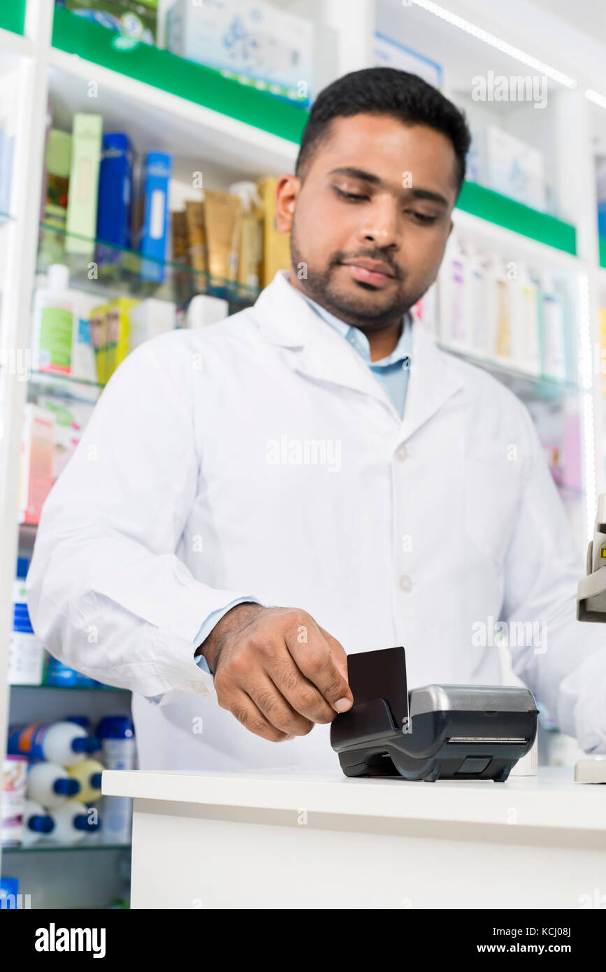 Junger Apotheker streichen Kreditkarte auf Reader Stockfoto