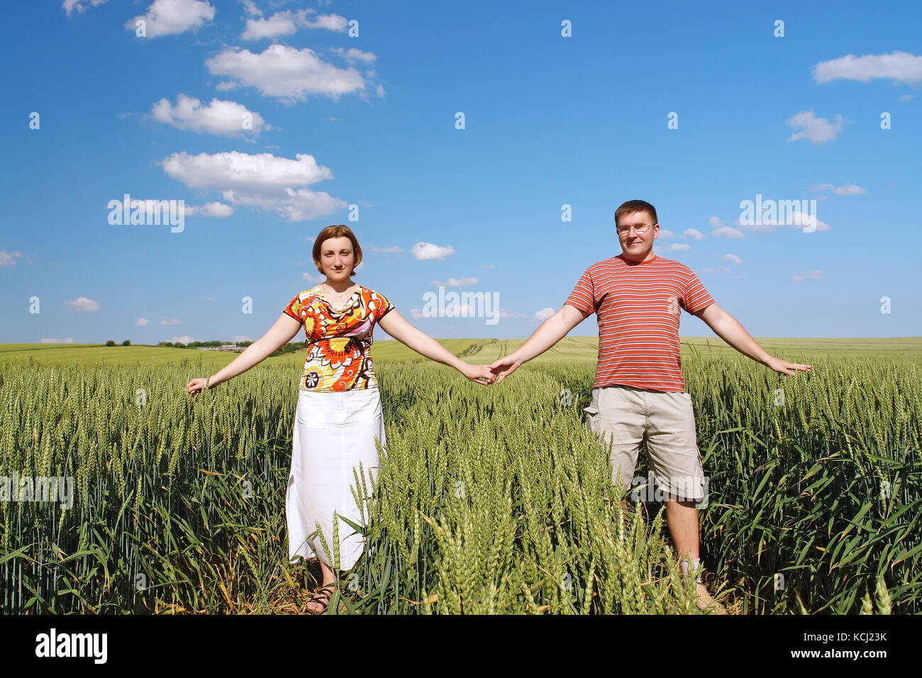 Junge Paare Holding mit Händen gerne posieren in Maisfeld Stockfoto